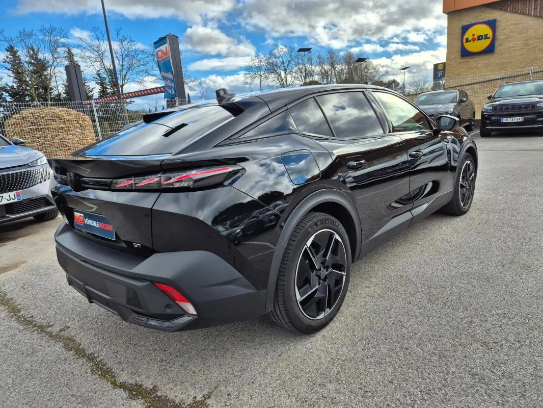 Vue 3/4 arrière droite d'une Peugeot 408 Hybrid GT noire 2024 avec jantes alliage 19 pouces et feux arrière LED distinctifs.