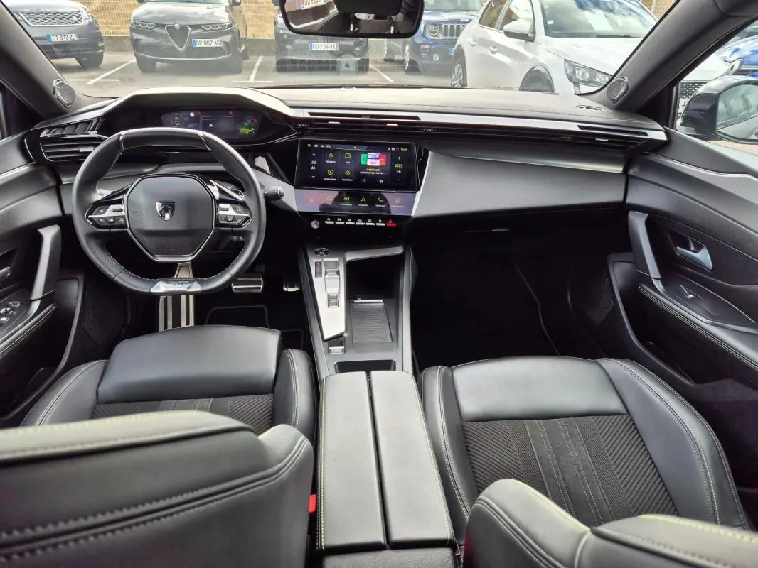 Intérieur noir du Peugeot 408 Hybrid 136 e-DCS6 GT vu de face, avec volant cuir, cockpit numérique et console centrale moderne.