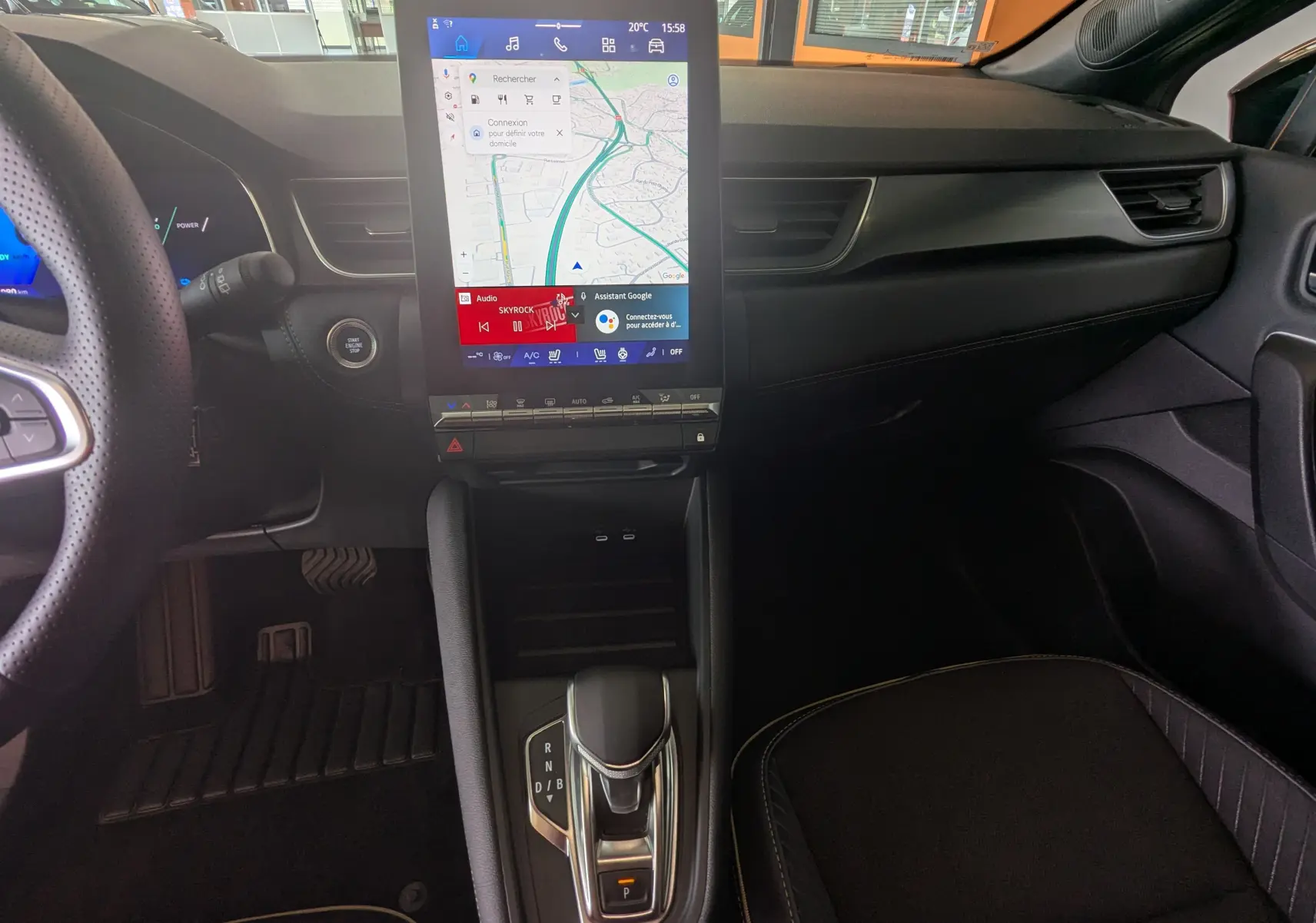 Vue intérieure centrée sur la console centrale et l’écran tactile vertical du Renault Symbioz gris Cassiopée, avec levier de vitesse automatique.
