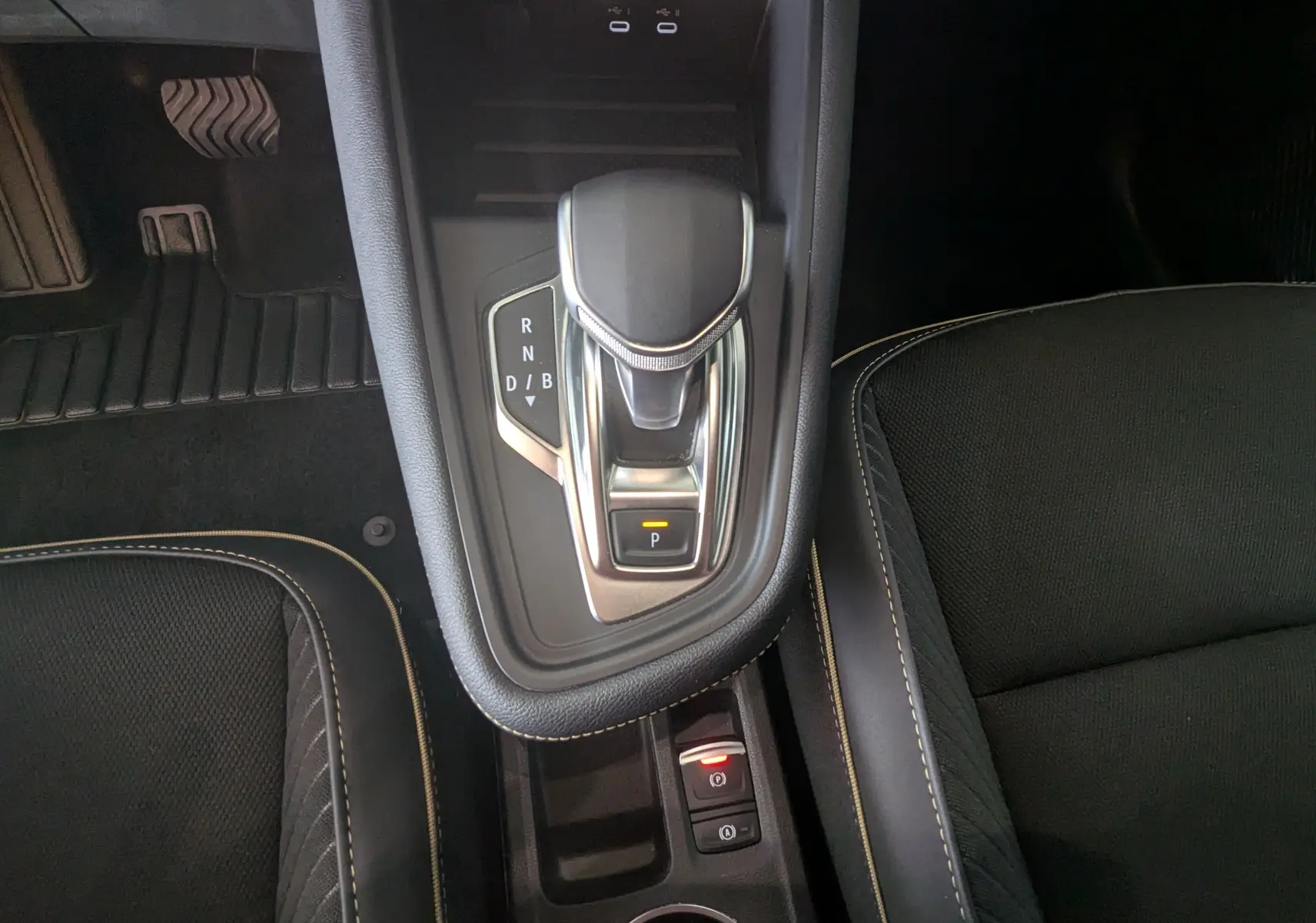 Vue plongeante sur la console centrale de la Renault Symbioz E-Tech Full Hybrid 145 Iconic avec levier de vitesse et sièges noirs.