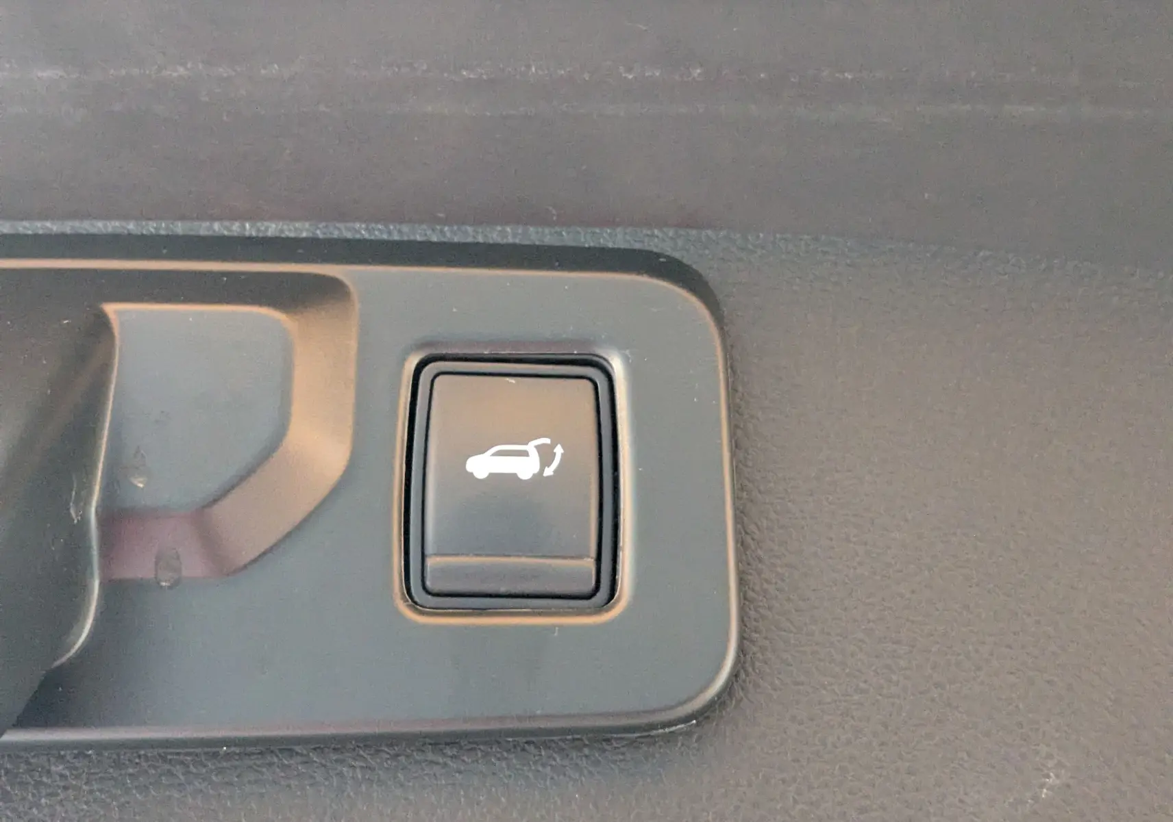 Bouton noir d'ouverture électrique du hayon sur tableau de bord intérieur du Renault Symbioz gris Cassiopée 2025.