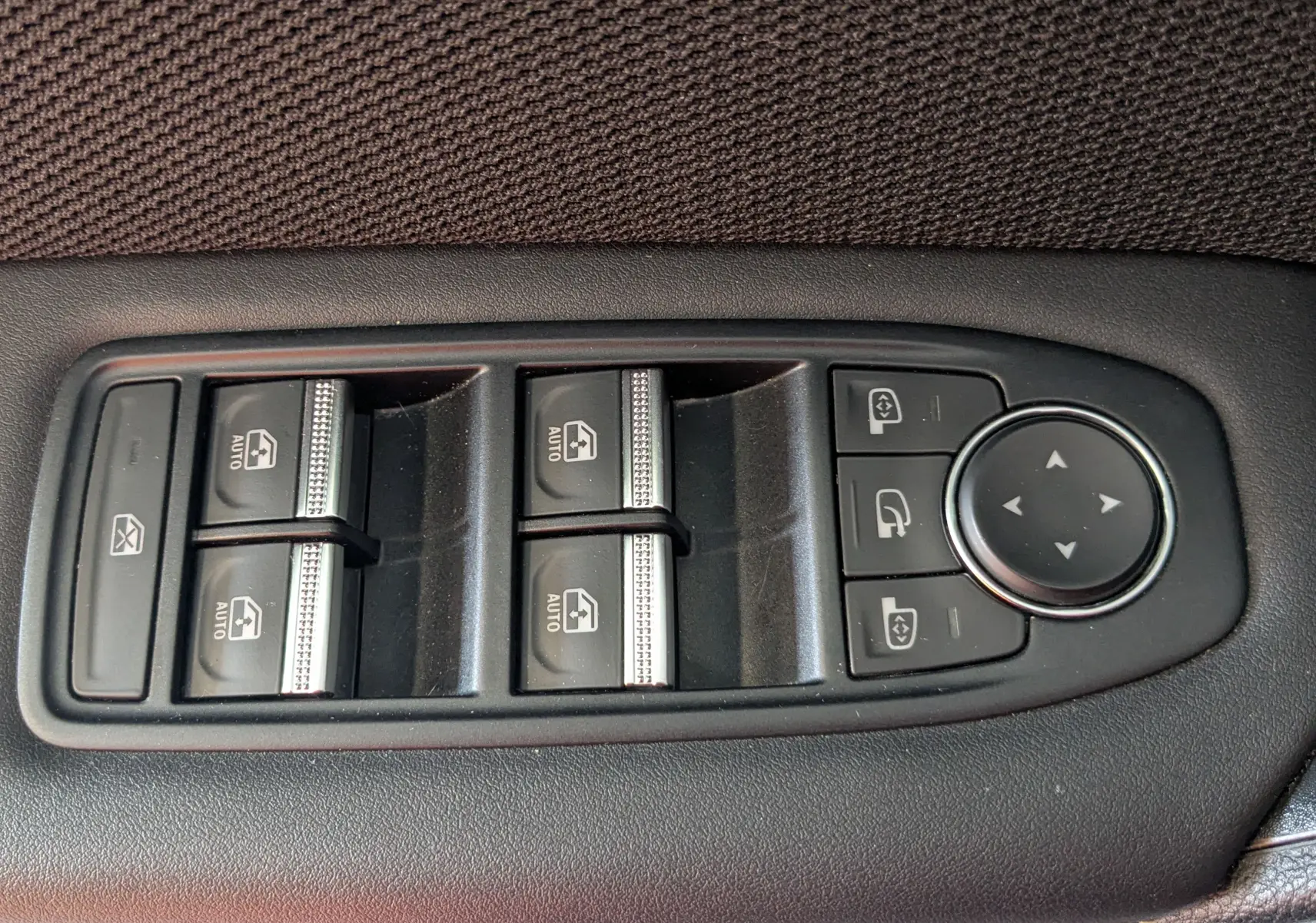 Panneau de commandes des vitres électriques et rétroviseurs sur portière intérieure en tissu gris du Renault Symbioz E-Tech Hybrid 2025.