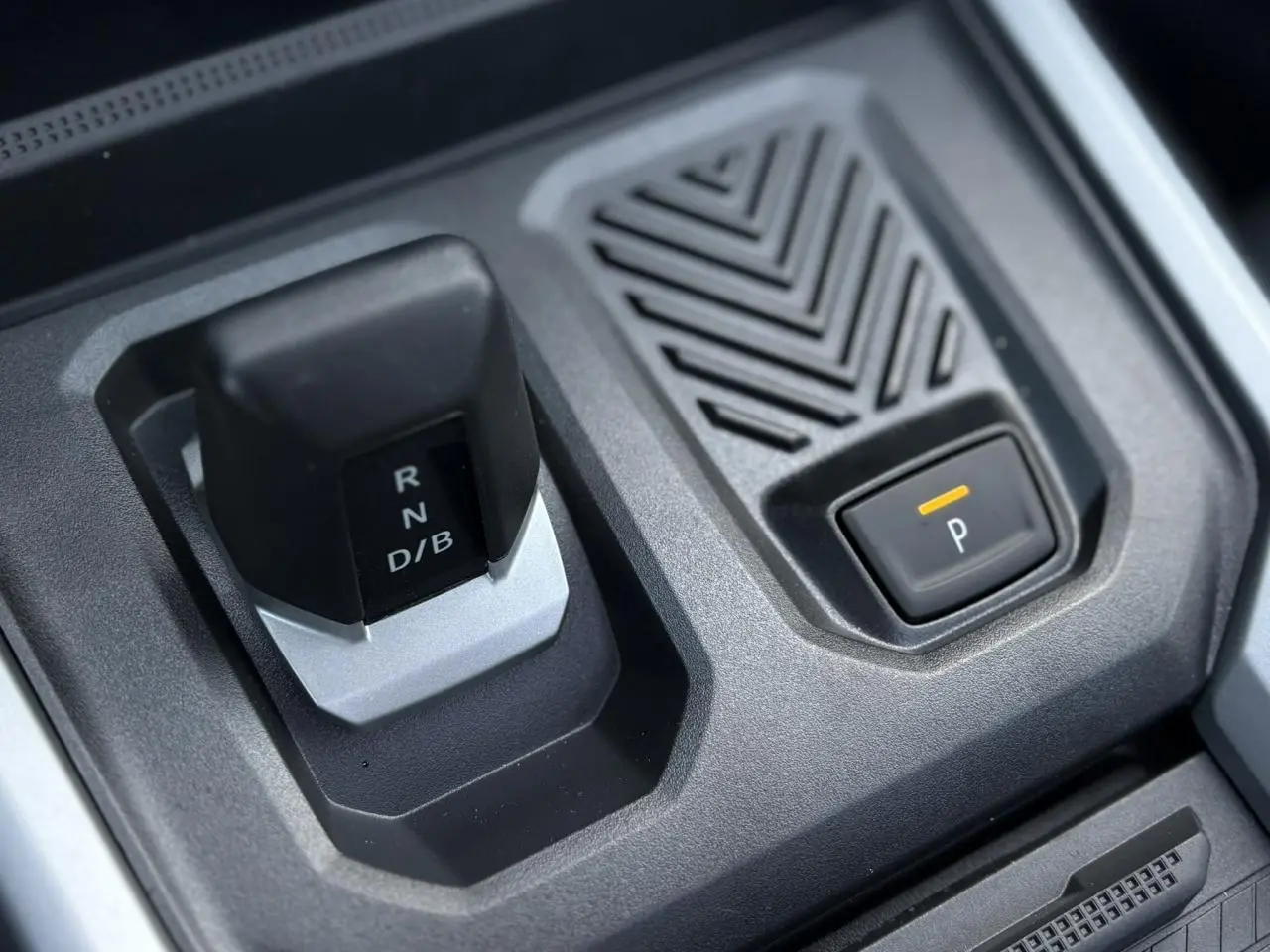 Gros plan sur la commande de boîte automatique et bouton de parking du Dacia Bigster 1.8 Hybrid noir nacré.