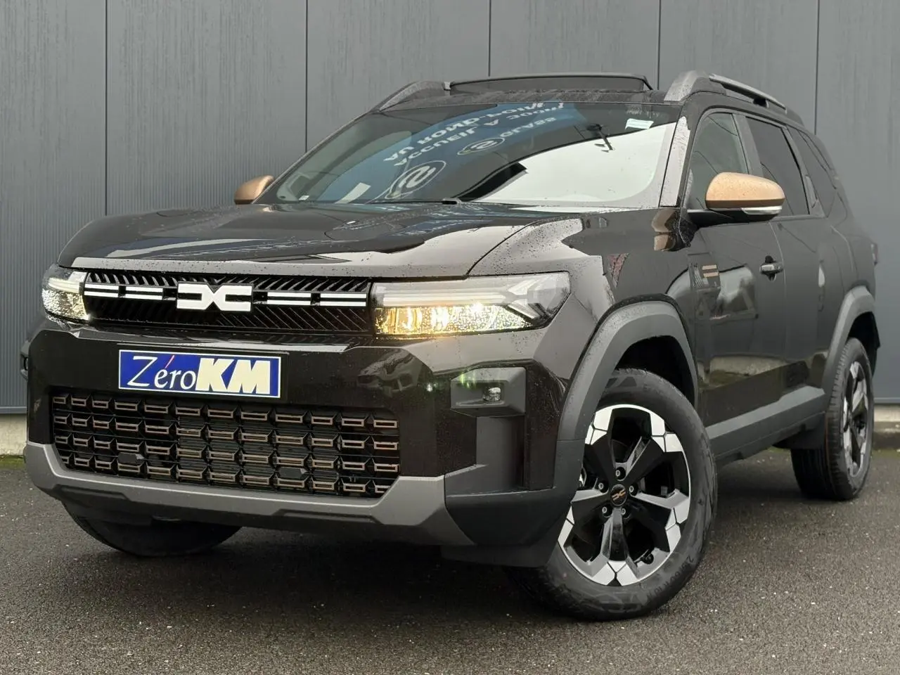 Vue 3/4 avant du Dacia Bigster 2026 noir nacré avec jantes 18'' et rétroviseurs cuivrés distinctifs.