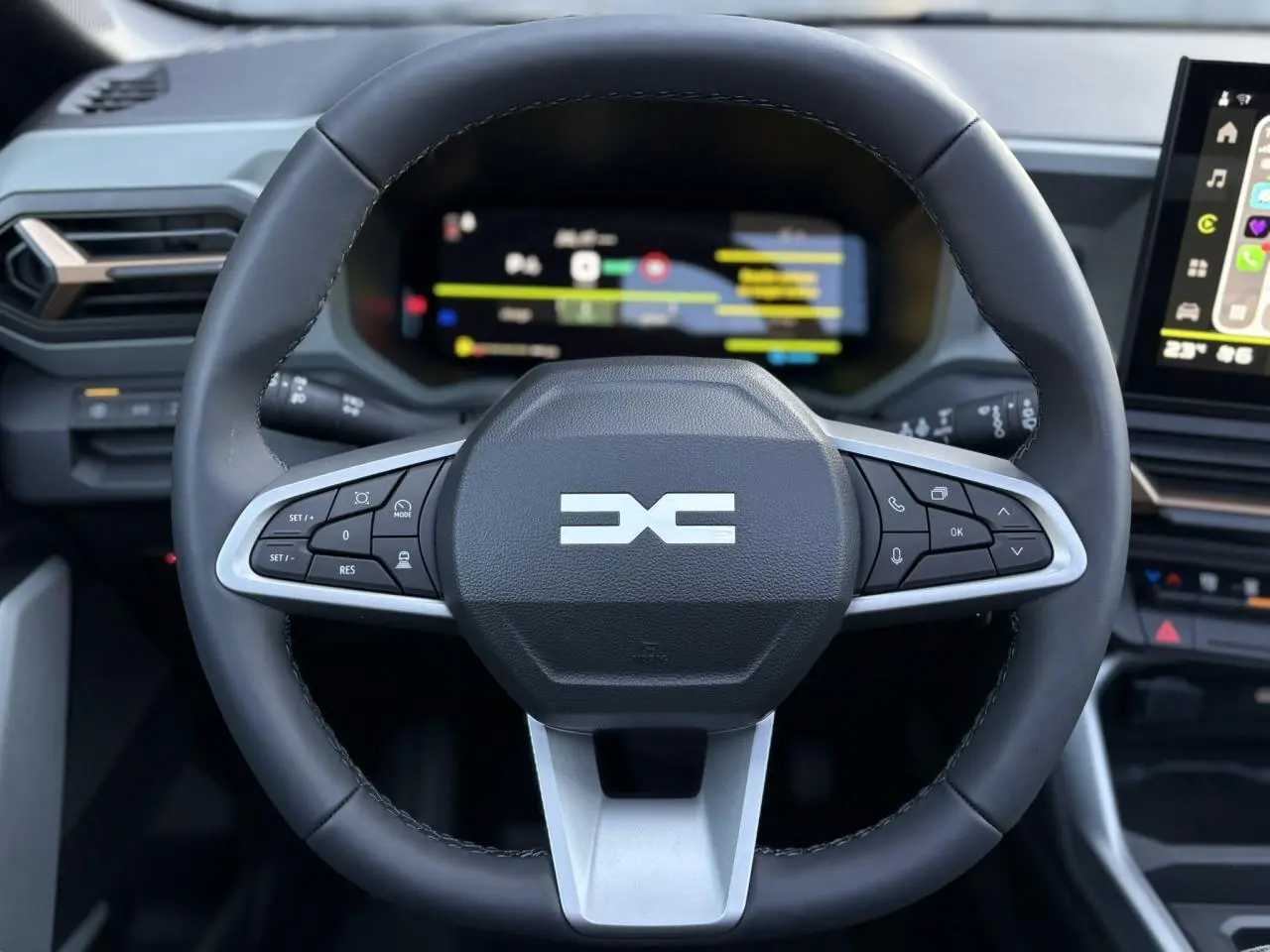 Vue rapprochée du volant multifonction noir du Dacia Bigster 2026 avec tableau de bord numérique en arrière-plan.