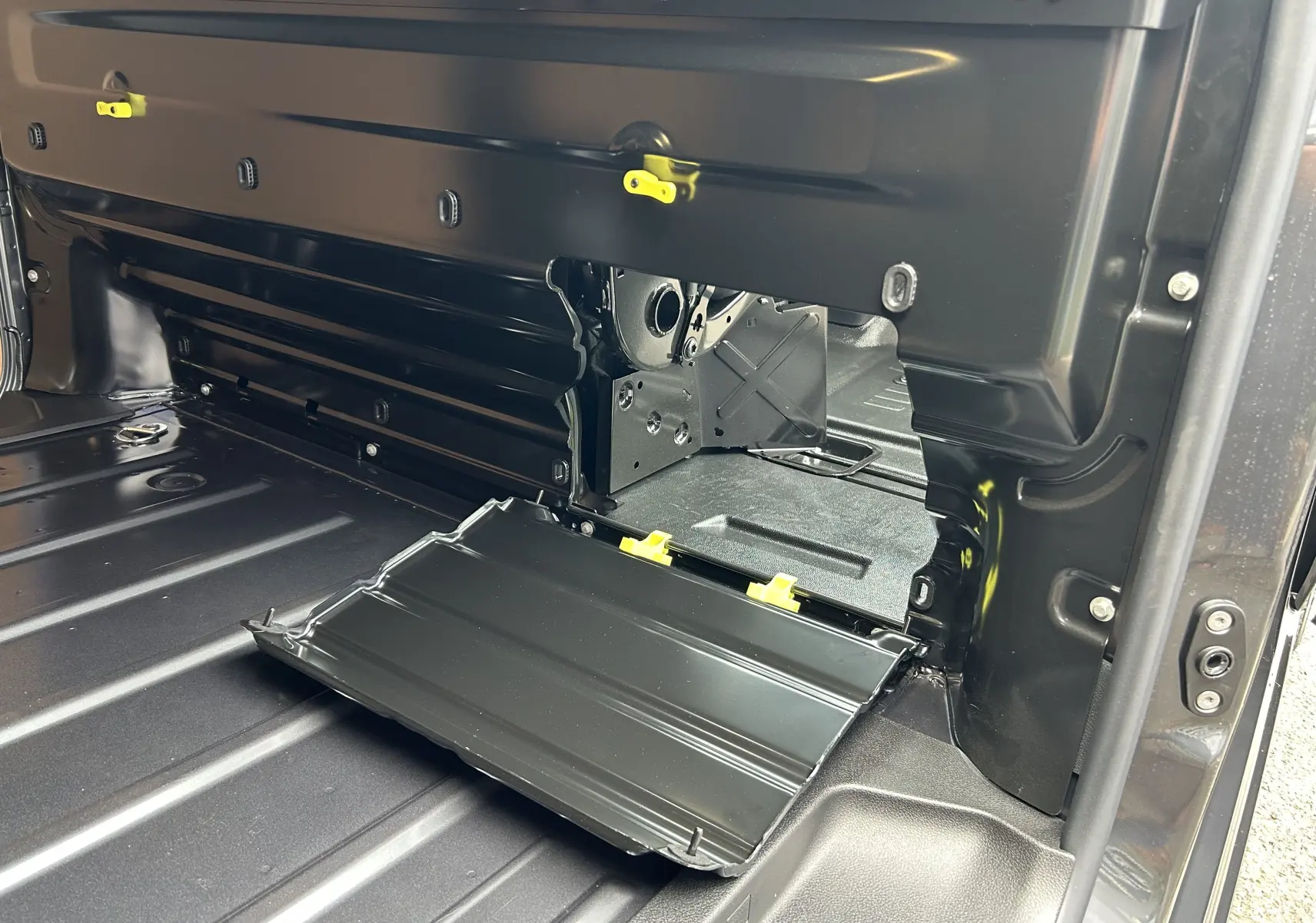 Détail intérieur du compartiment de chargement arrière du Citroën Jumpy Fourgon gris acier, avec trappe ouverte et fixations jaunes visibles.