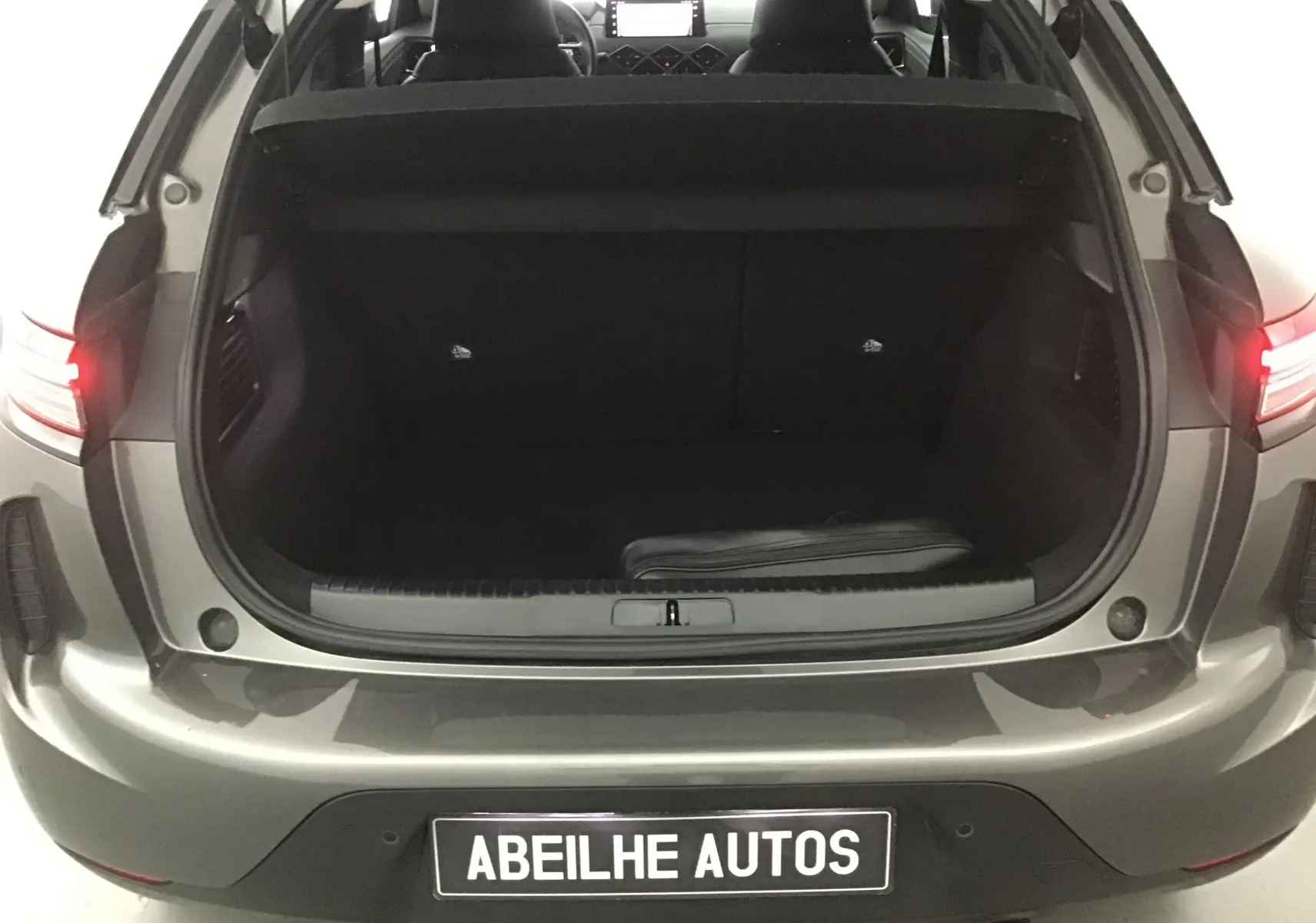 Coffre ouvert vu de l'arrière d'un DS3 Crossback gris platinium 2024, intérieur noir et feux arrière allumés.