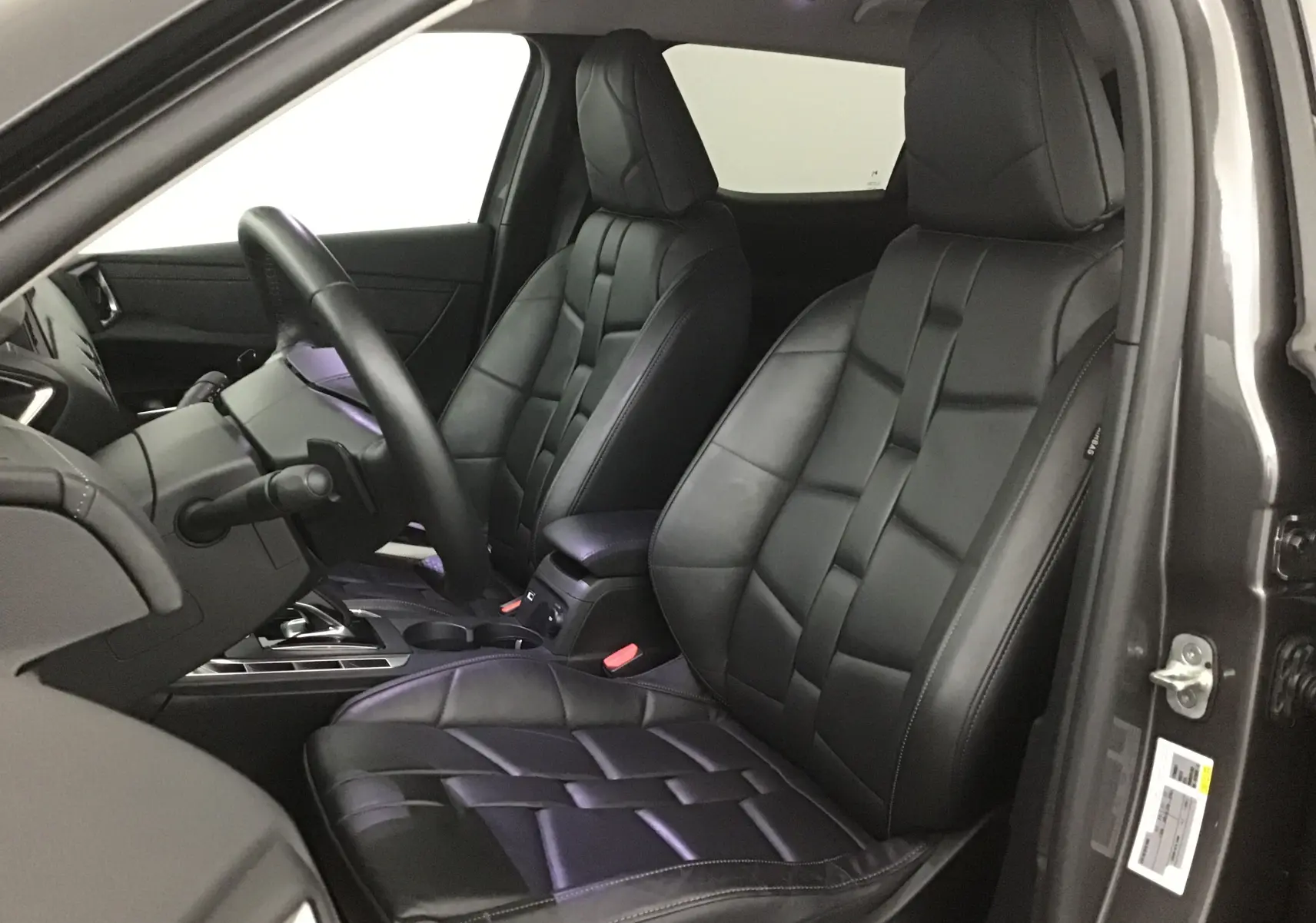 Intérieur du DS3 Crossback 2024 gris platinium, vue côté conducteur sur sièges cuir noir au design matelassé.