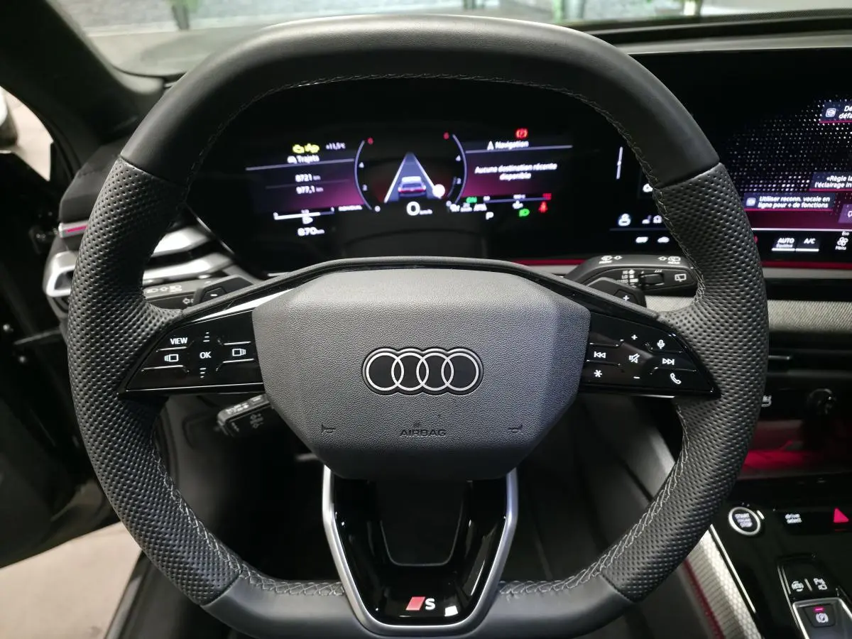 Volant sport en cuir avec commandes multifonctions et logo S de l'Audi A5 Avant noir, vue centrée depuis le siège conducteur.