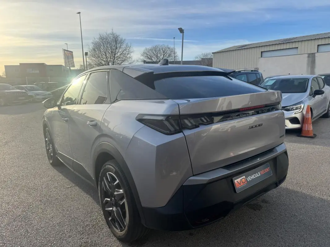 Vue 3/4 arrière droite d’un Peugeot 3008 Hybrid gris 2025 avec jantes alliage noires de 19 pouces et vitres teintées.