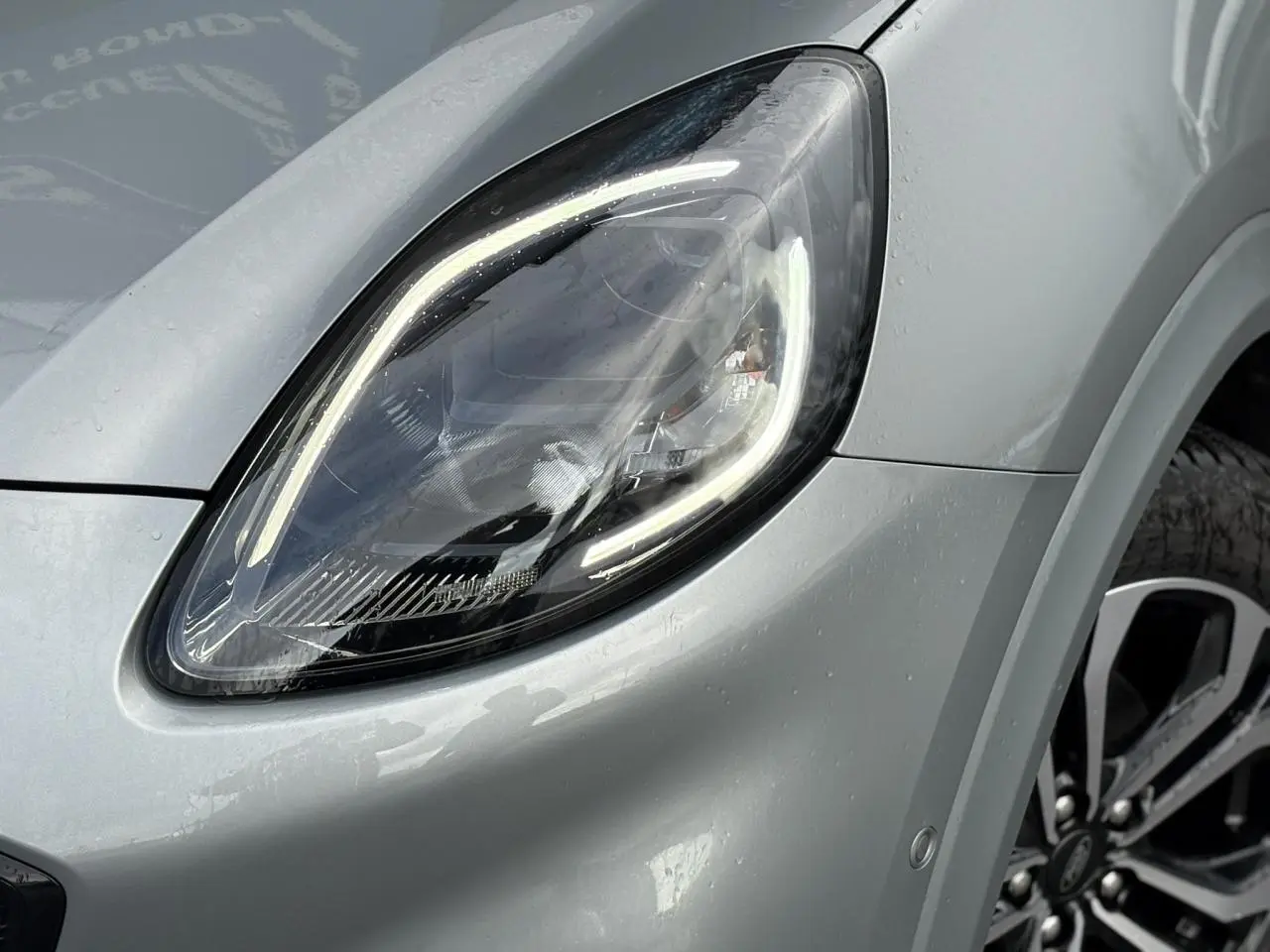 Gros plan sur le phare avant gauche du Ford Puma gris Solar avec jante alliage et carrosserie brillante.