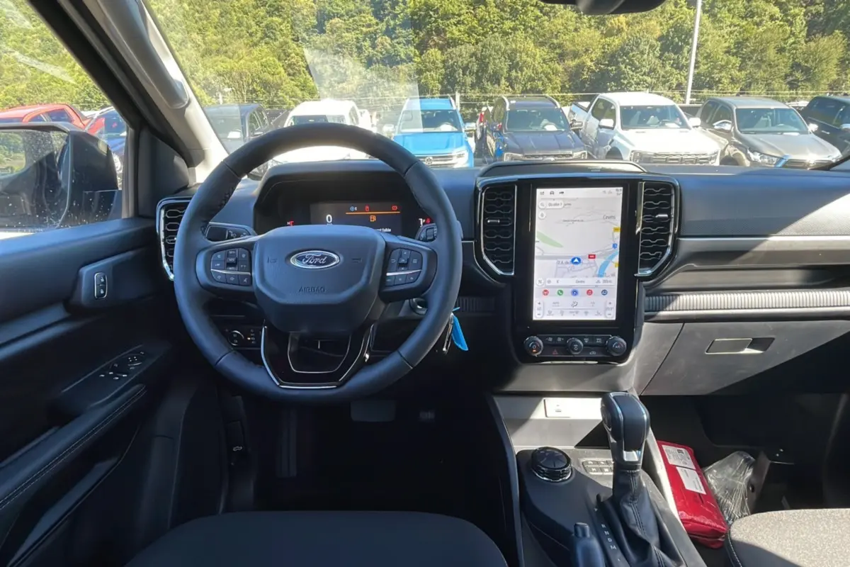 Vue intérieure avant du Ford Ranger 2025 noir shadow, volant cuir multifonctions et écran tactile vertical avec navigation GPS.
