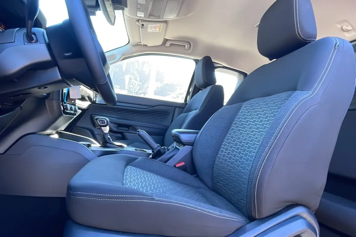 Vue intérieure côté conducteur du Ford Ranger 2025, sièges tissu gris avec surpiqûres blanches et console centrale visible.