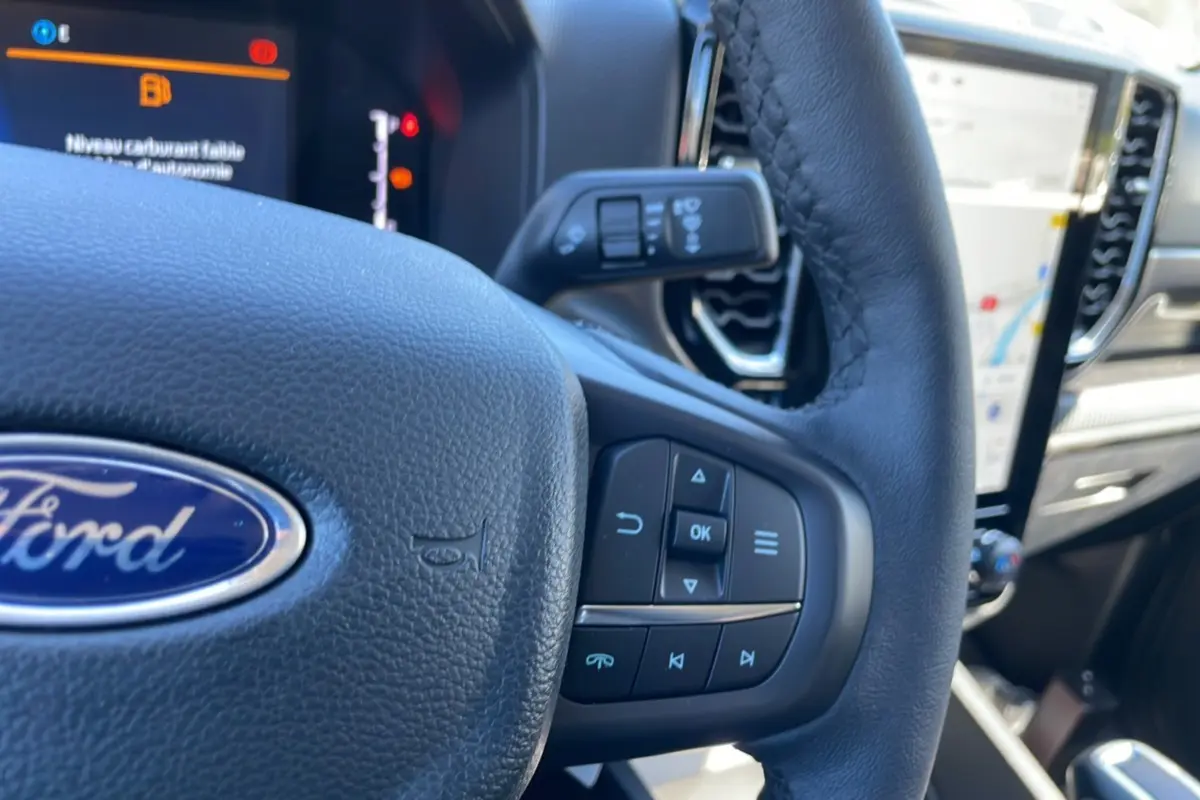 Gros plan sur le volant cuir multifonctions du Ford Ranger 2025, avec écran tactile et commandes au volant visibles.