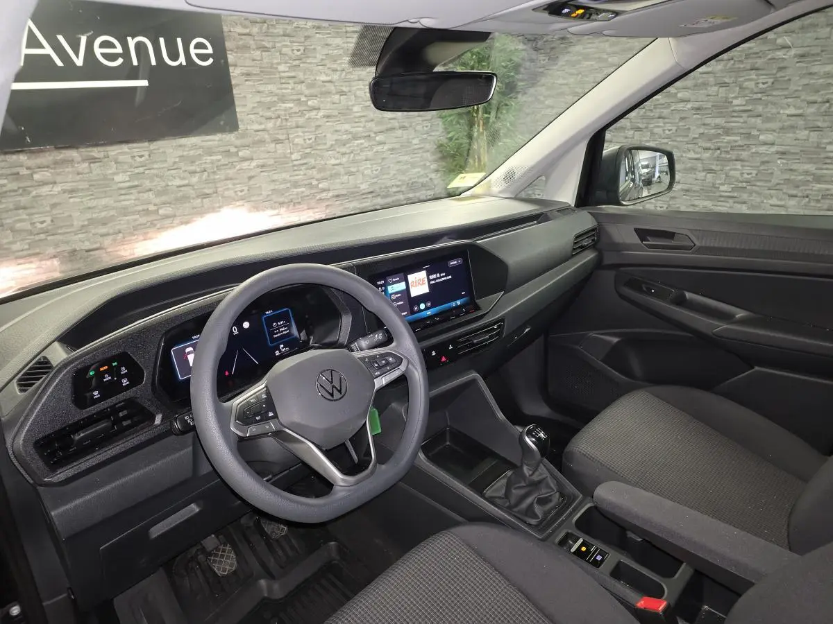 Vue intérieure côté conducteur du Volkswagen Caddy 2024 noir, avec tableau de bord digital et volant multifonction.
