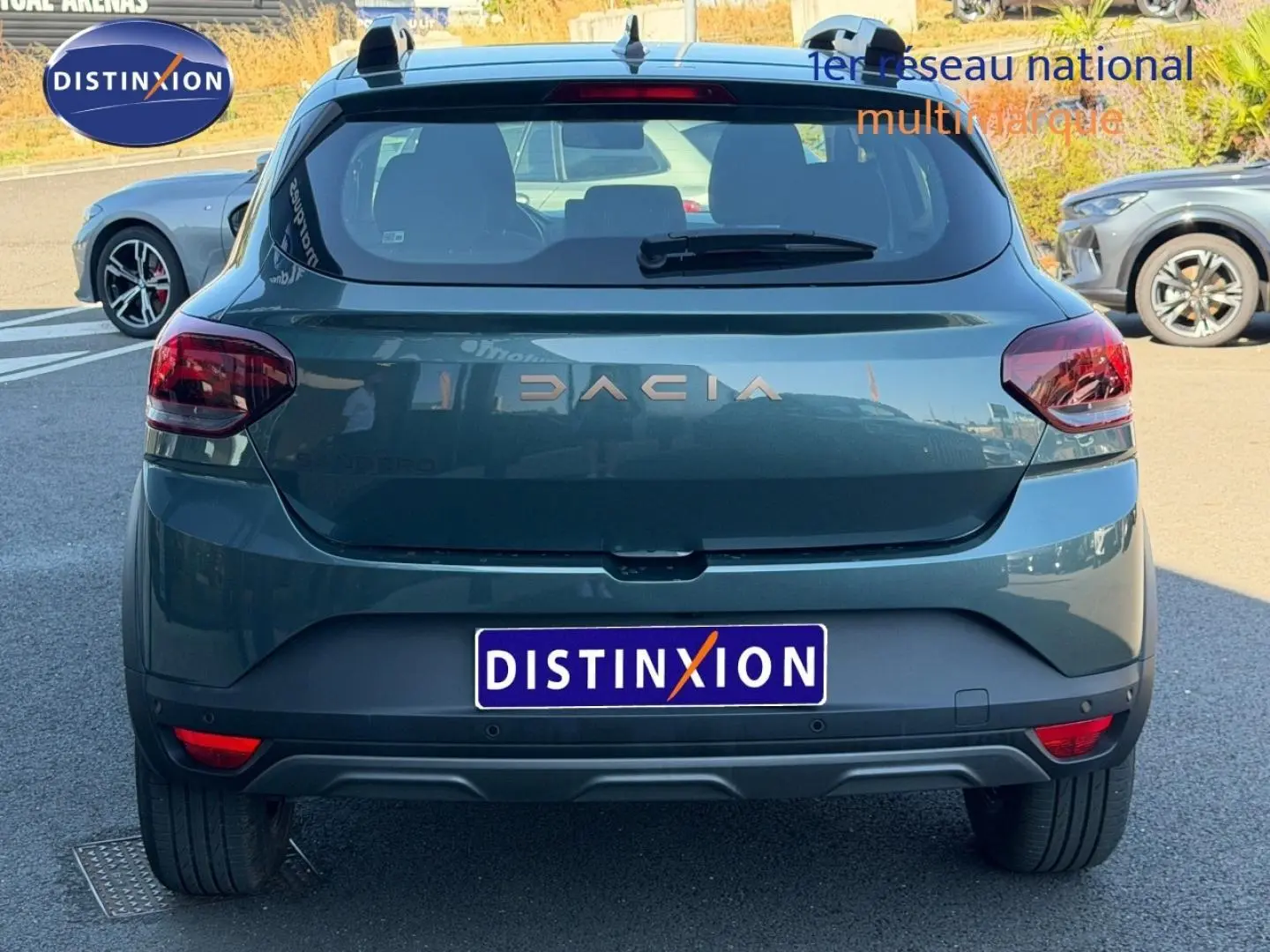 Vue arrière d'une Dacia Sandero 2025 vert cèdre métallisé avec logo DACIA et feux arrière LED visibles.