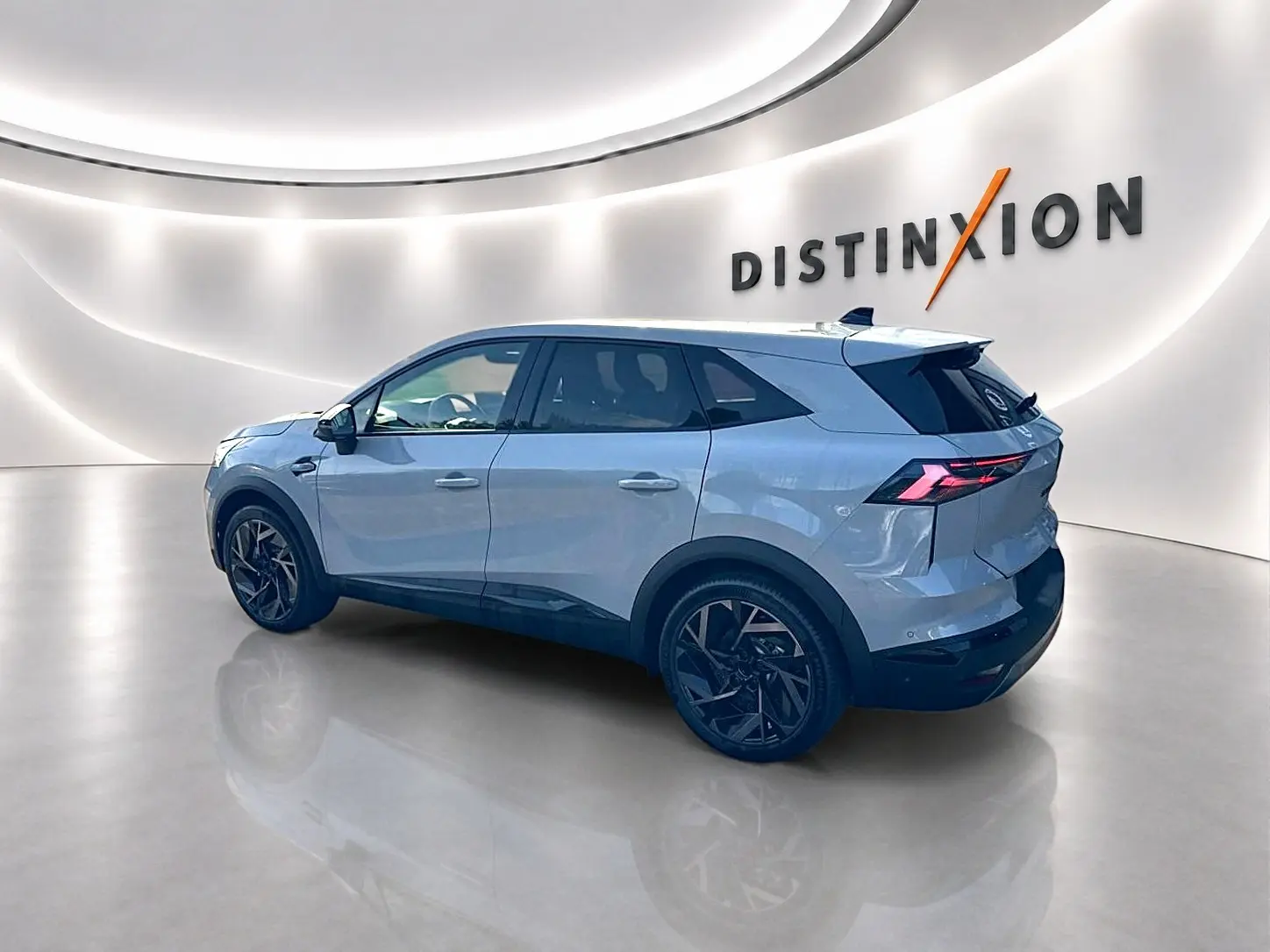 Renault Symbioz gris rafale en vue 3/4 arrière droit, avec jantes noires et feux arrière LED distinctifs.