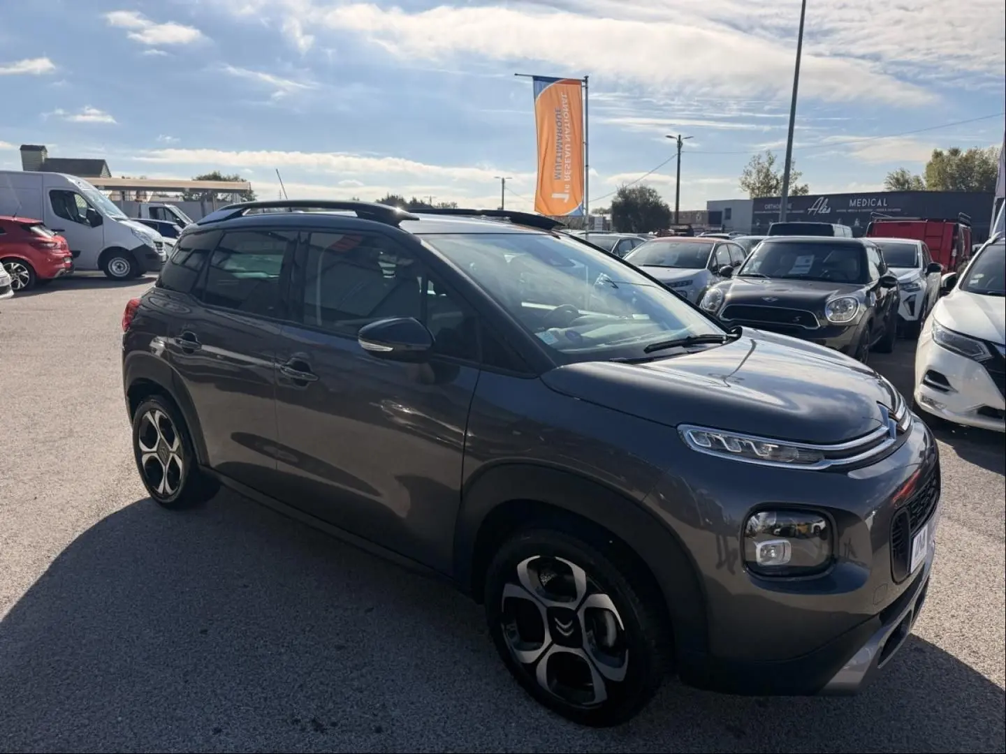 Citroën C3 Aircross gris métal vue 3/4 avant droit, avec jantes distinctives et toit noir contrasté.