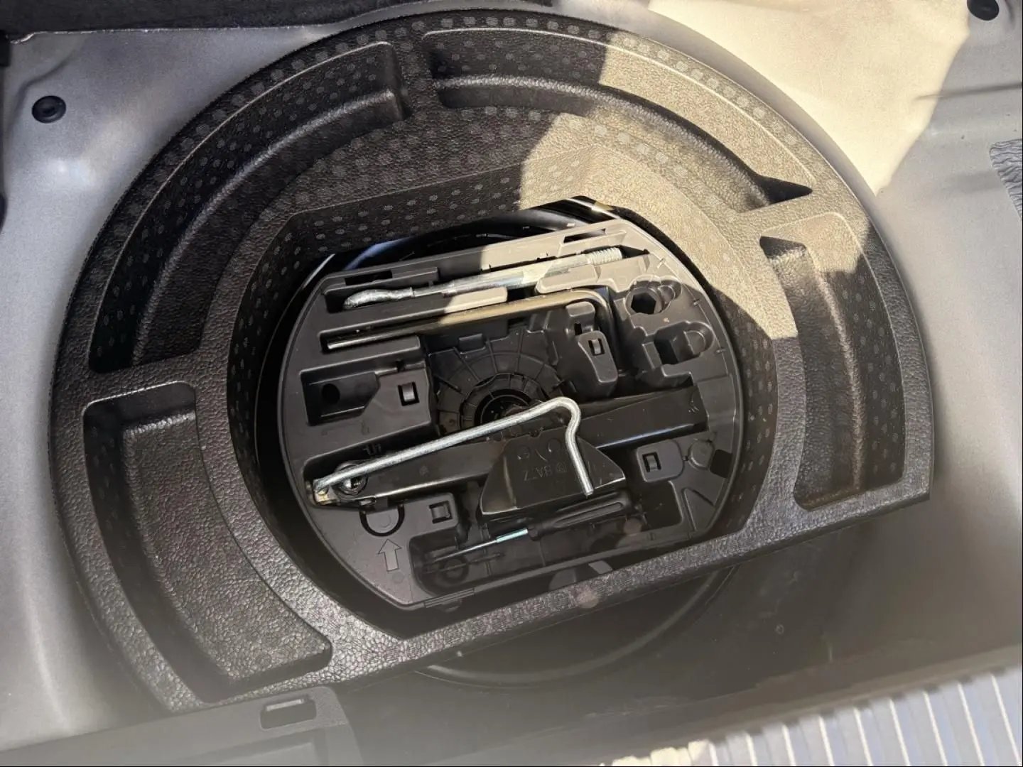 Vue plongeante sur le rangement sous coffre d'un Citroën C3 Aircross gris métal 2021, avec outils de dépannage visibles.