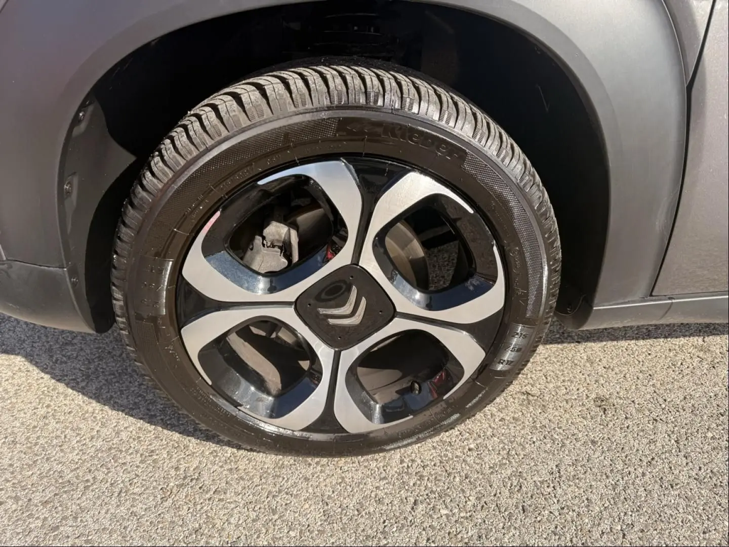 Gros plan sur la roue avant droite du Citroën C3 Aircross gris métal, avec jante alliage noire et argentée distinctive.