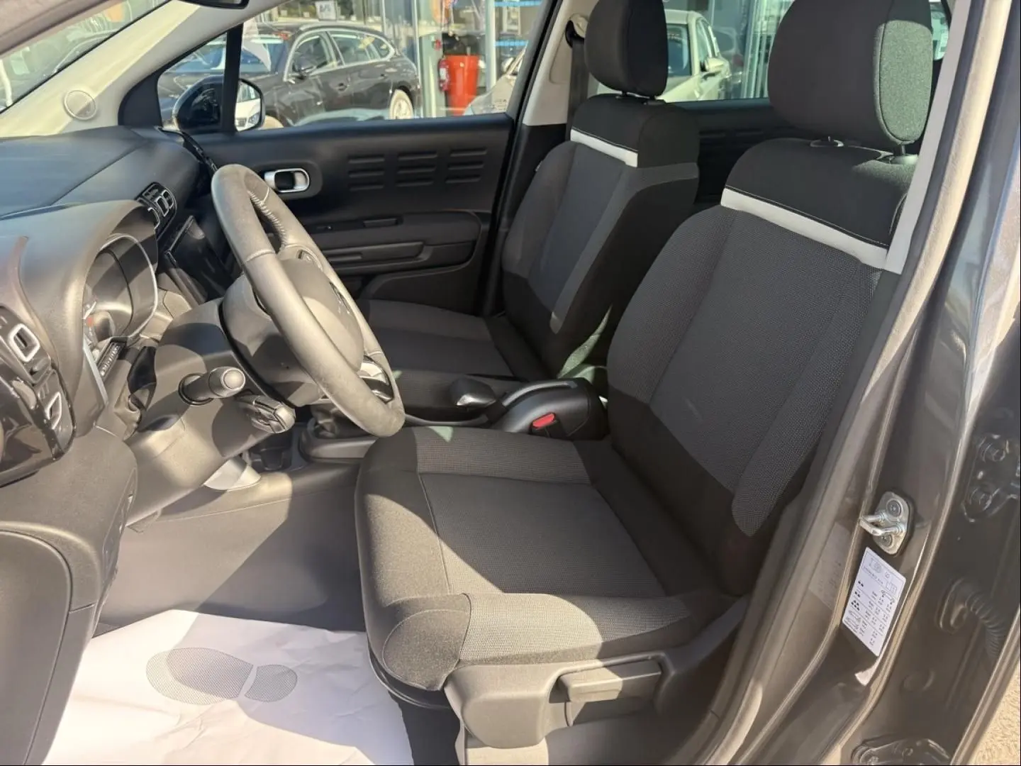 Vue intérieure côté conducteur du Citroën C3 Aircross gris métal 2021, sièges tissu bicolore et volant multifonction.