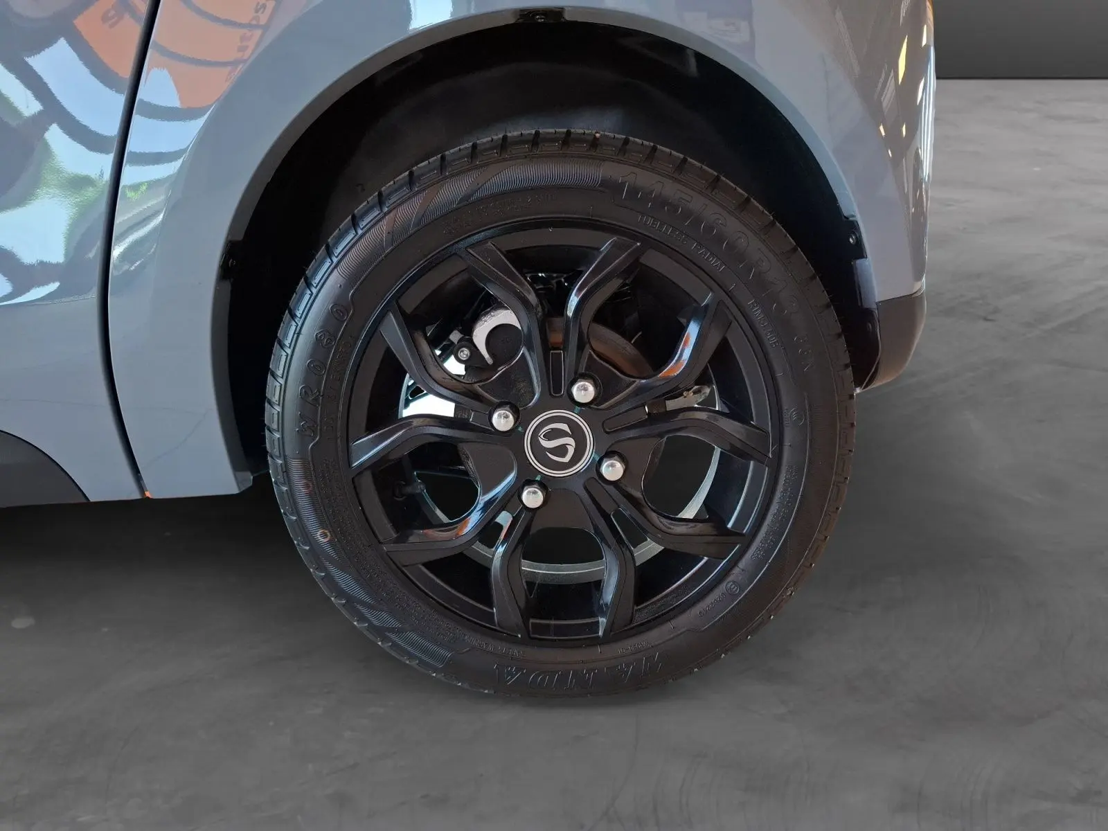 Gros plan sur la roue arrière droite noire à jante stylisée du SIMPLICI S1 gris perle avec toit noir.