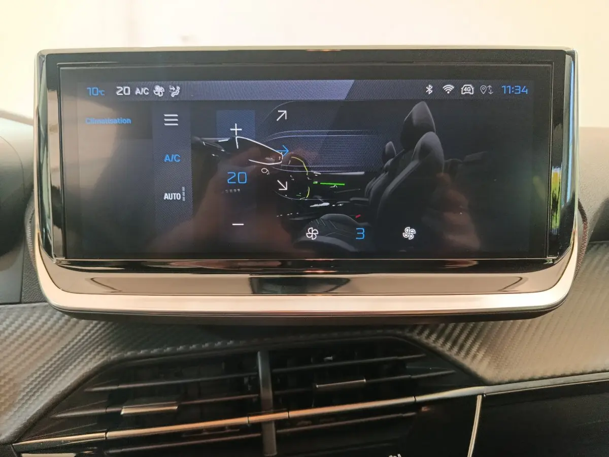 Écran tactile central affichant la climatisation à 20°C dans l'habitacle d'une Peugeot 208 gris foncé.