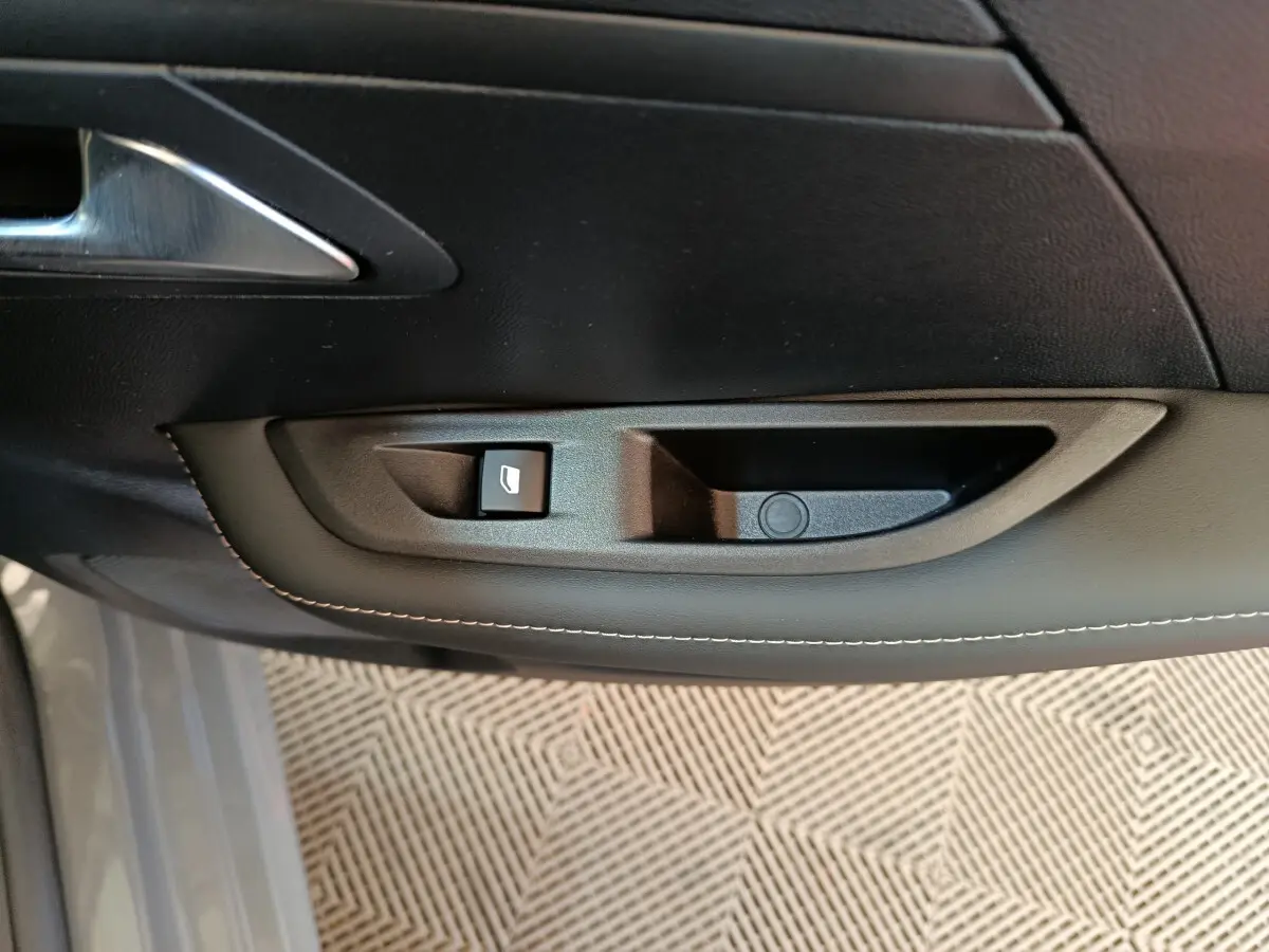 Poignée intérieure côté gauche avec commande de lève-vitre sur porte d'une Peugeot 208 gris foncé 2025.