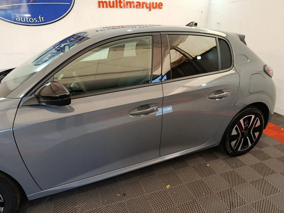 Profil côté gauche de la Peugeot 208 gris foncé avec jantes alliage et rétroviseurs noirs brillants.