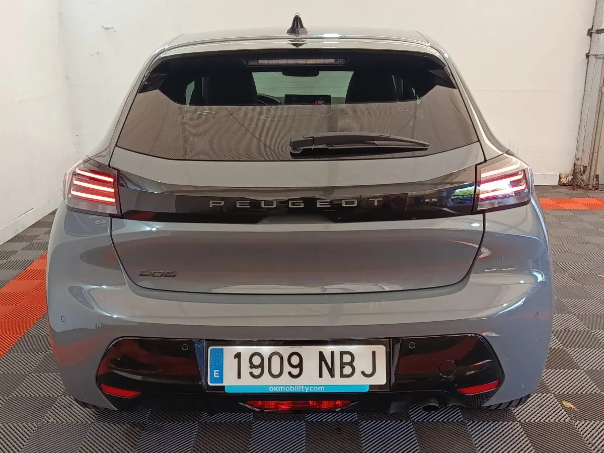 Vue arrière d'une Peugeot 208 gris foncé avec feux LED allumés dans un garage.