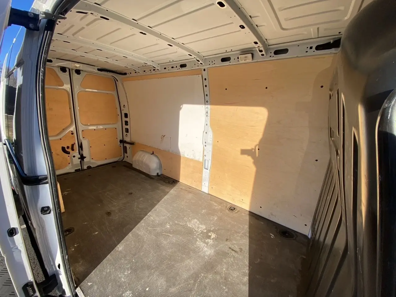 Vue intérieure de la zone de chargement du fourgon blanc Nissan Interstar L3H2, avec parois et sol protégés par un revêtement bois.