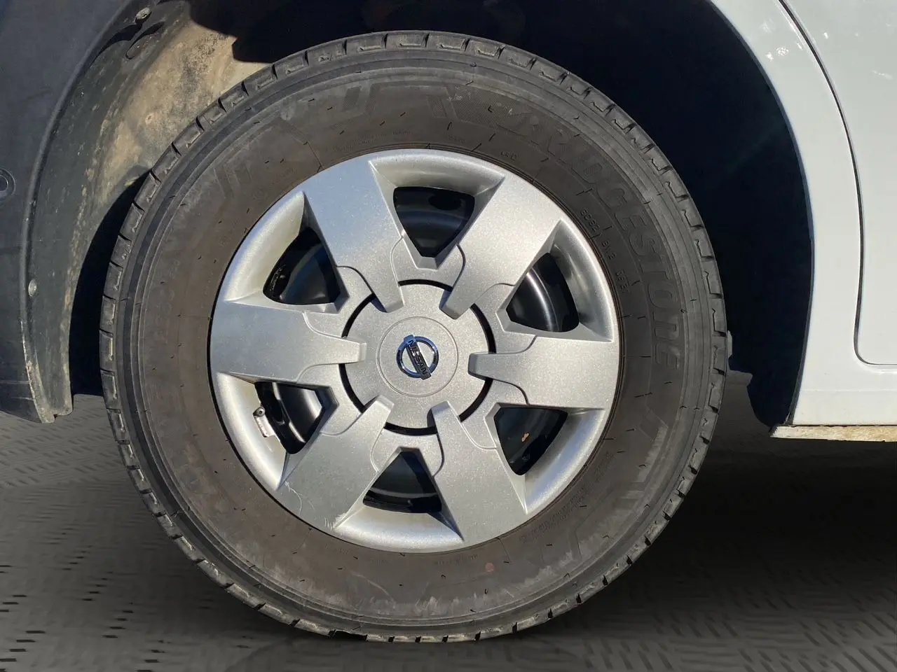 Gros plan sur la roue avant gauche du Nissan Interstar blanc, mettant en valeur la jante avec logo Nissan au centre.