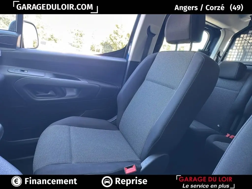 Intérieur du Peugeot Rifter 2024, siège avant droit en tissu gris et noir, vue côté passager avec porte et fenêtre visibles.