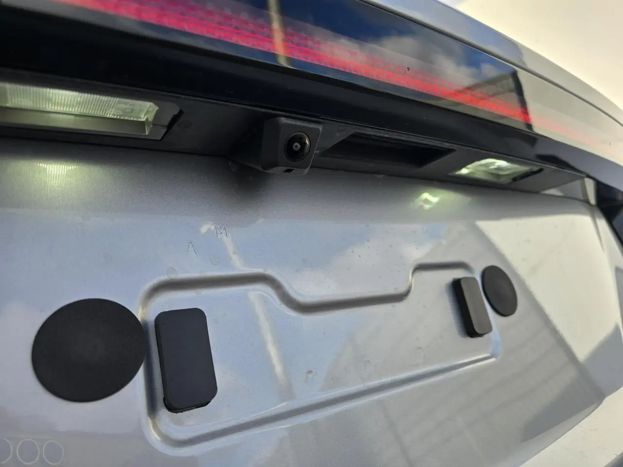 Gros plan sur la caméra de recul et la plaque d'immatriculation arrière du Hyundai Tucson 2025 en Shimmering Silver Metal.