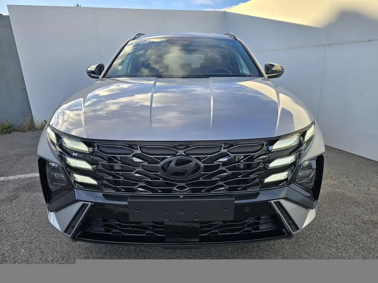 Vue frontale du Hyundai Tucson 2025 en argent métallisé avec calandre noire N Line et feux LED distinctifs.