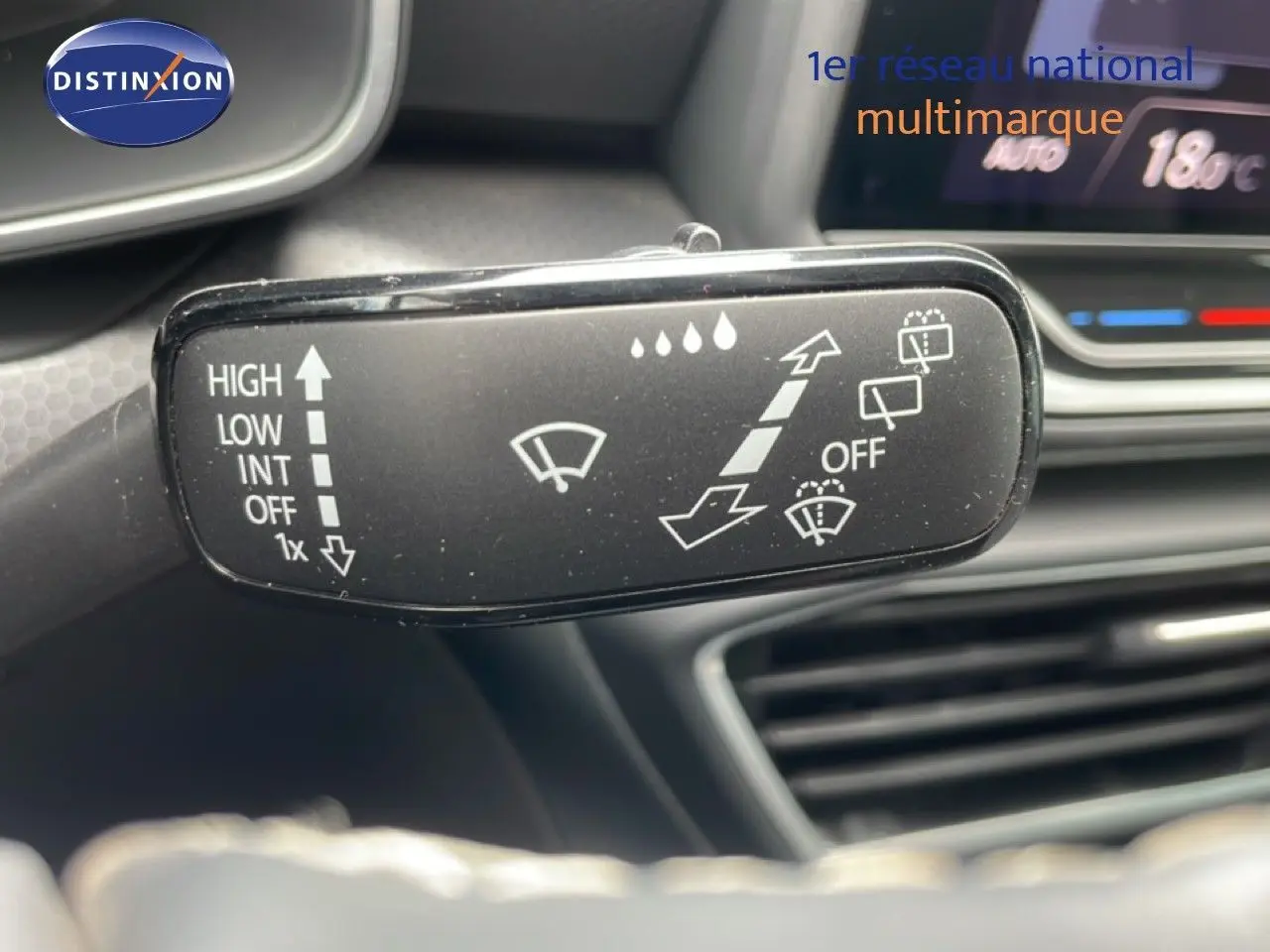 Gros plan sur la commande d’essuie-glace dans l’habitacle du SEAT Leon blanc neige métal, avec tableau de bord en arrière-plan flou.