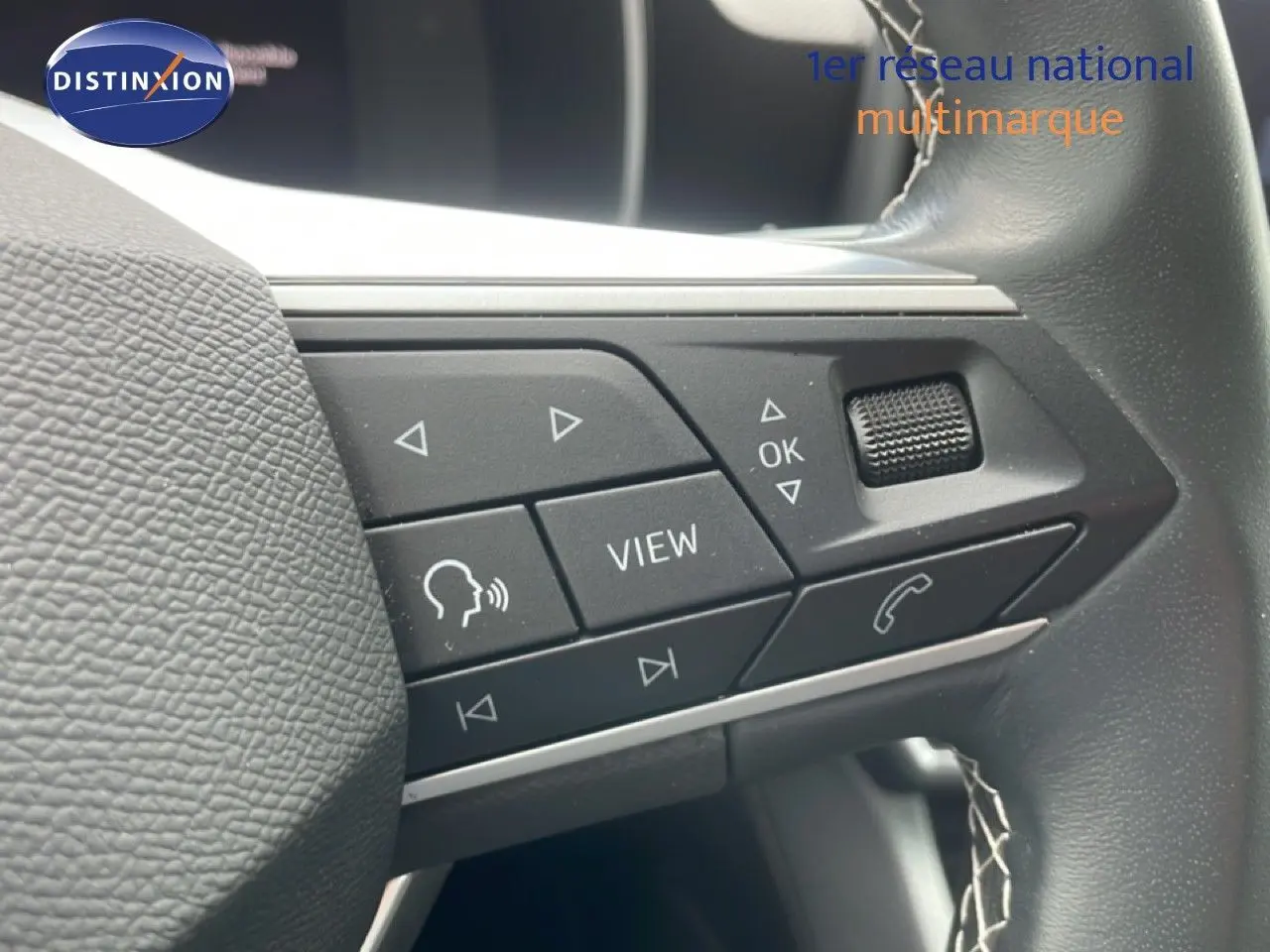 Gros plan sur les commandes multifonctions à droite du volant en cuir noir du SEAT LEON blanc neige métal.