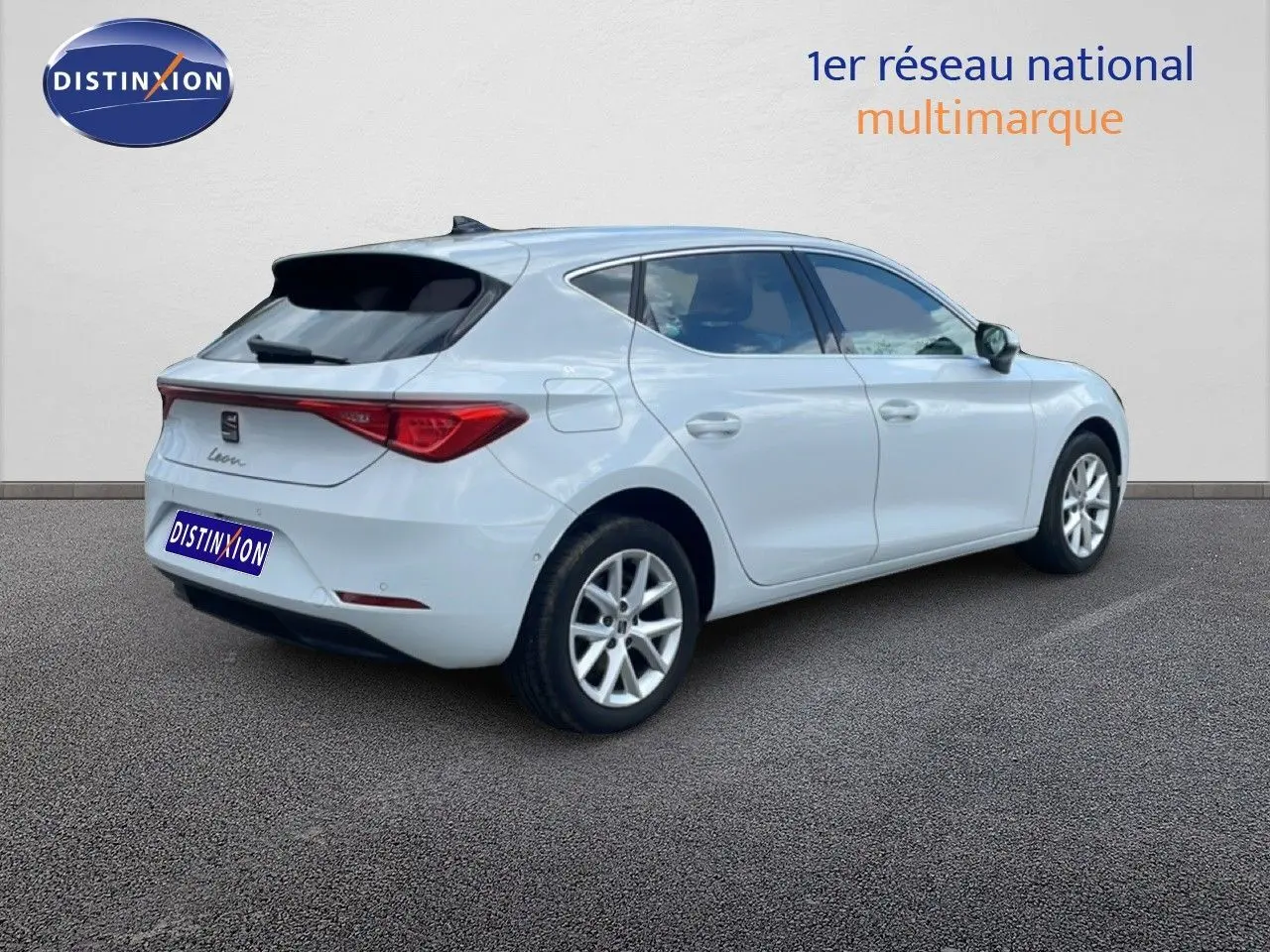 Vue 3/4 arrière droite d'une SEAT Leon blanche neige métal, avec jantes alliage et vitres teintées.