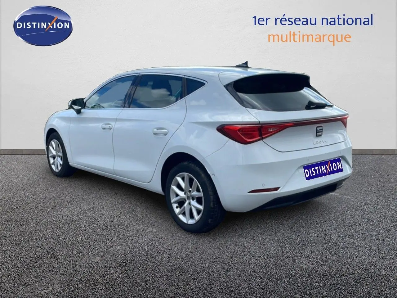 Vue 3/4 arrière droite d'une SEAT Leon blanche neige métal, avec feux arrière LED et jantes alliage.