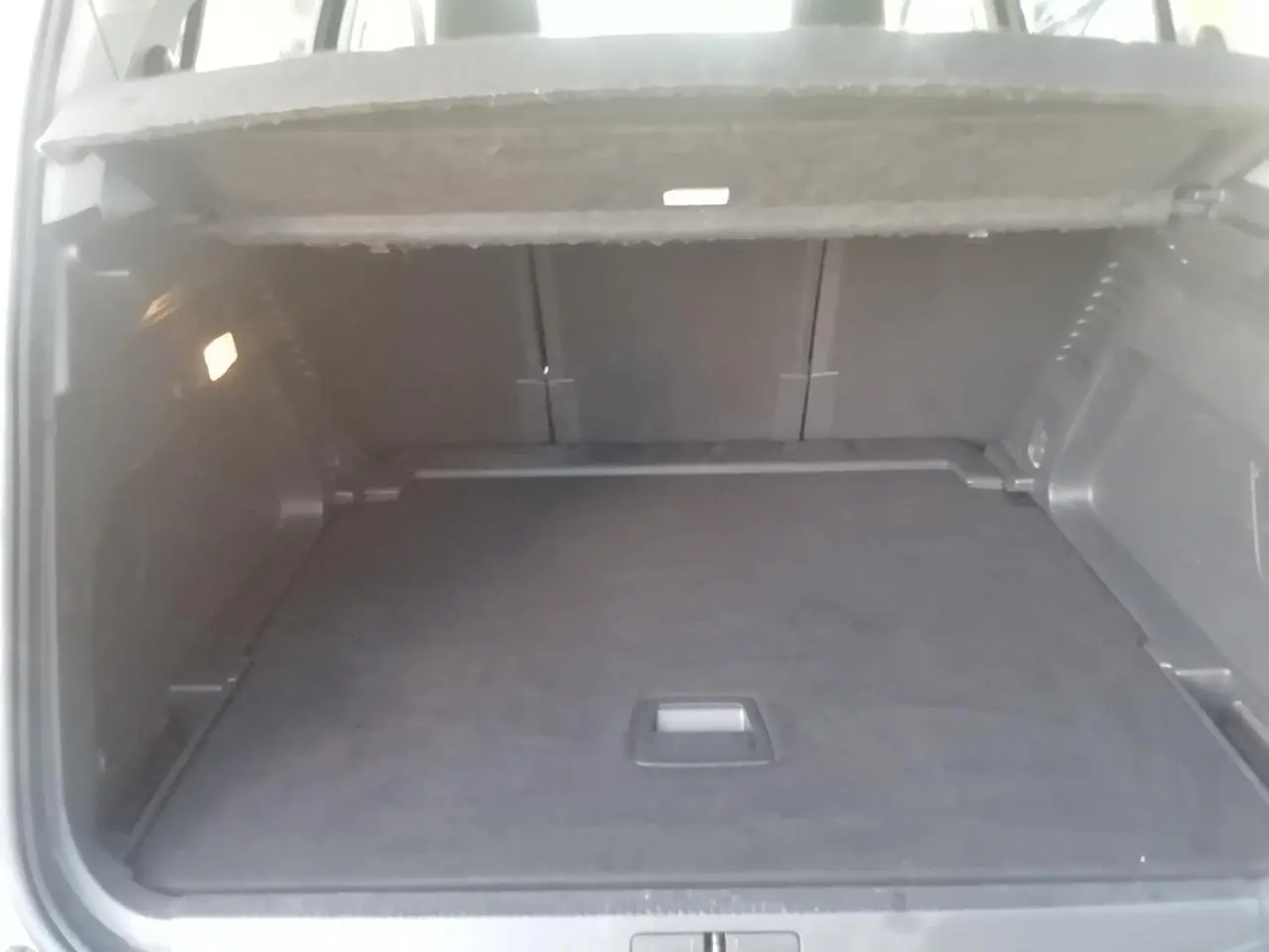 Vue intérieure du coffre spacieux et propre du Citroën C5 Aircross gris, avec plancher plat et éclairage latéral.