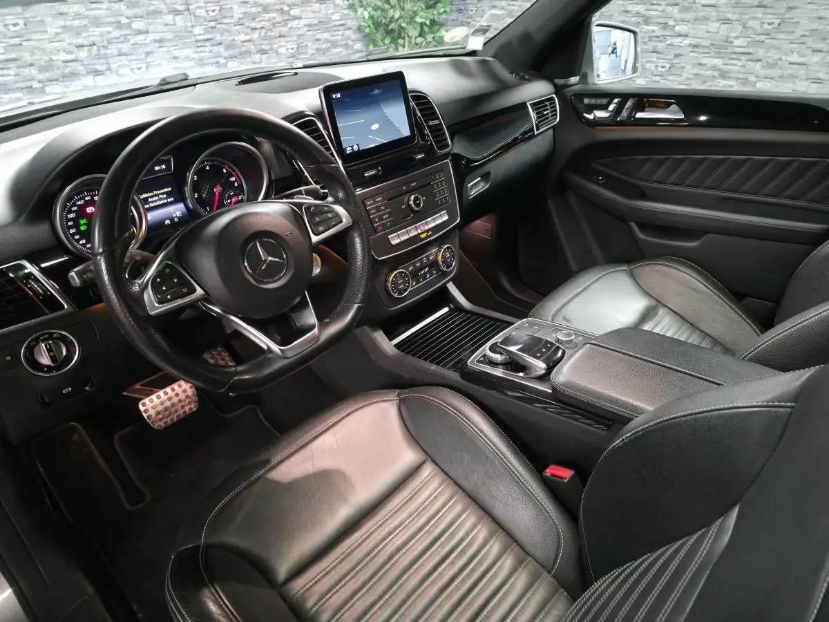 Vue intérieure côté conducteur du Mercedes GLE 350 d AMG Line 2016, avec sièges cuir noirs et tableau de bord moderne.