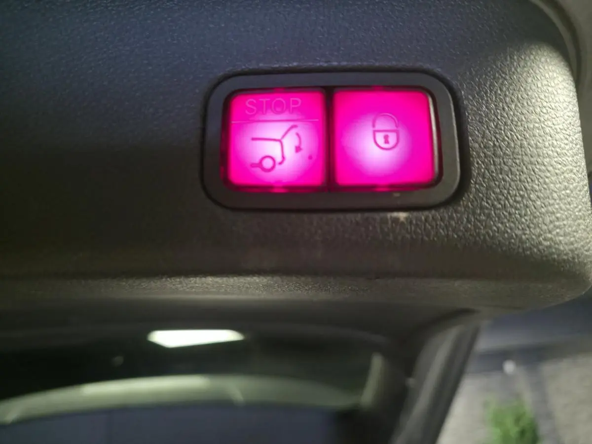 Gros plan sur les boutons lumineux roses de fermeture et arrêt du hayon électrique du Mercedes GLE 350 d gris clair.