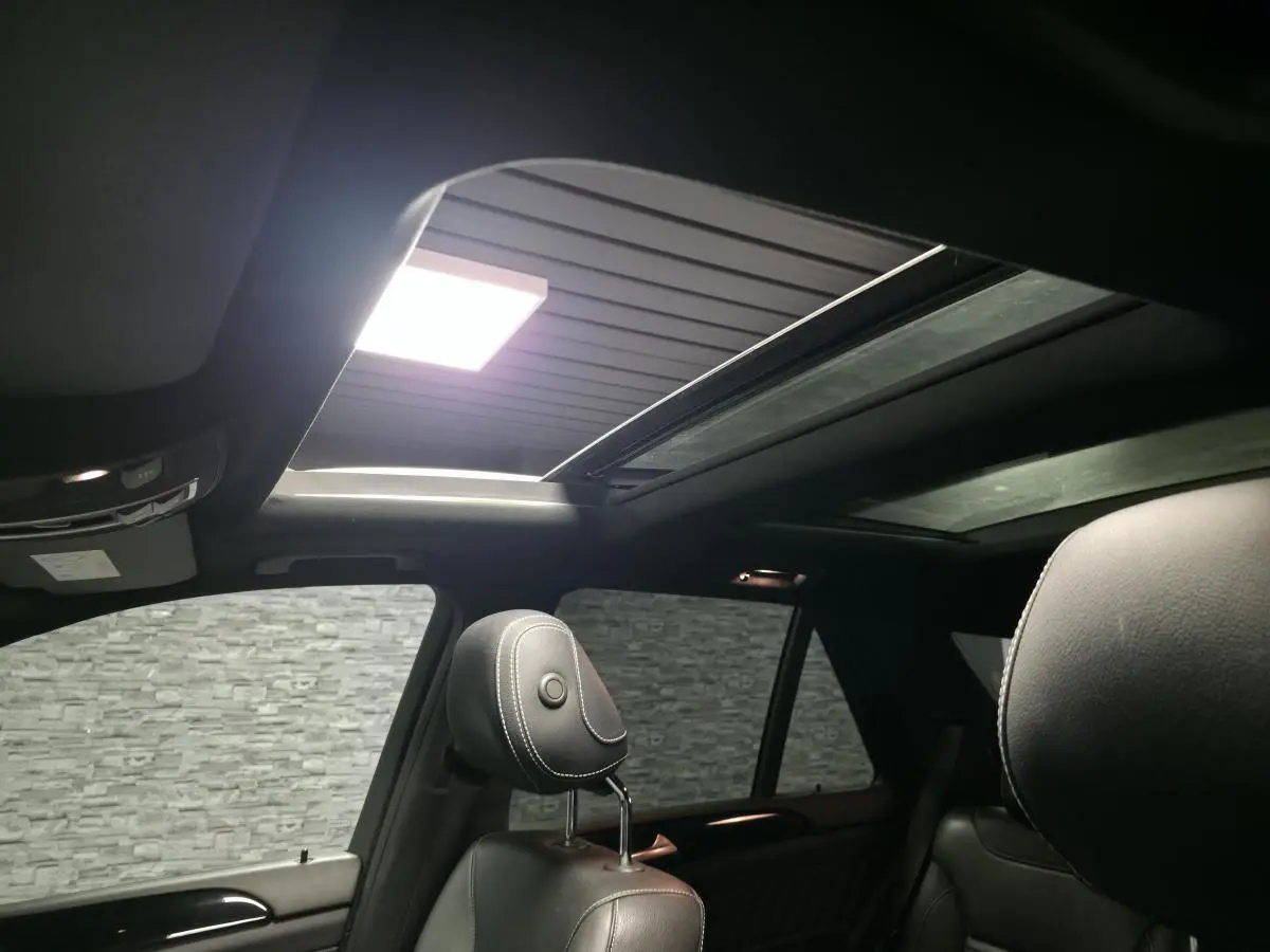 Toit ouvrant panoramique ouvert vu de l'intérieur arrière d'un Mercedes GLE 350 d gris clair avec sièges en cuir noir.