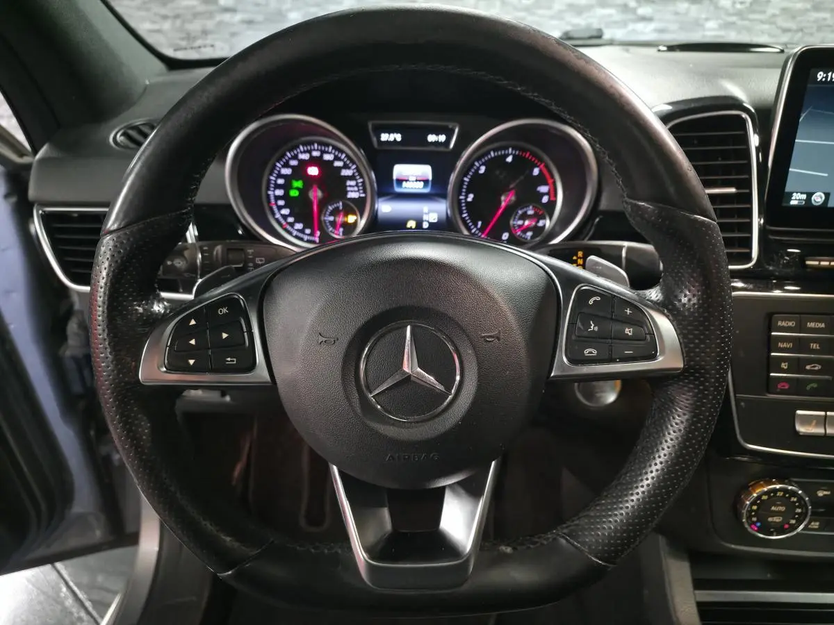 Vue intérieure centrée sur le volant cuir perforé Mercedes du GLE 350 d avec tableau de bord et commandes visibles.
