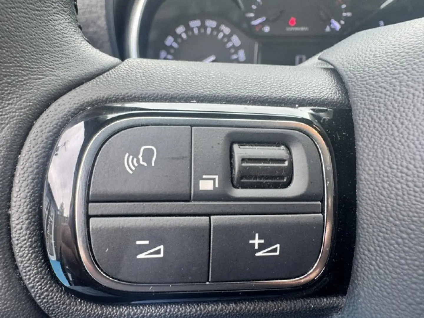 Gros plan sur les commandes vocales et volume sur le volant cuir noir du Citroën C3 Aircross gris acier 2024.