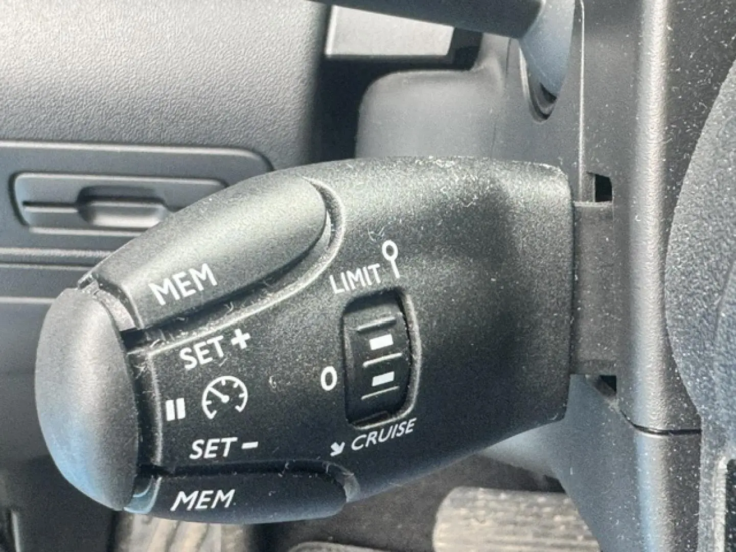 Gros plan sur la commande de régulateur de vitesse côté gauche du volant du Citroën C3 Aircross gris acier.