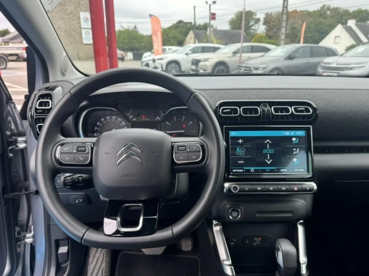 Vue intérieure centrée sur le volant cuir et l’écran tactile du tableau de bord du Citroën C3 Aircross gris acier 2024.