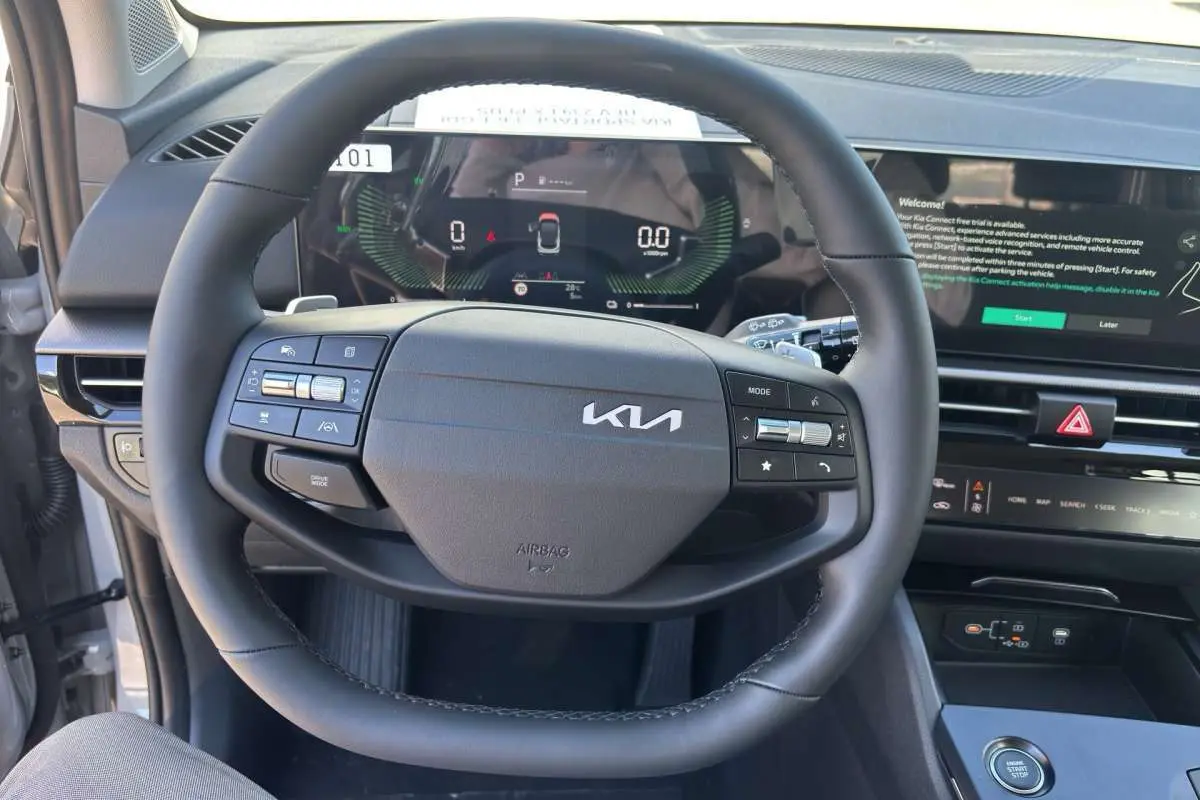 Vue intérieure centrée sur le volant cuir multifonctions noir du Kia Sportage 2026 avec tableau de bord digital et écran tactile.