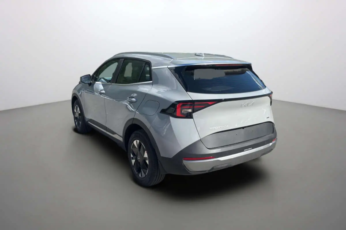 KIA Sportage 2026 gris céramique vu 3/4 arrière droit, feux arrière LED et jantes alu 17 pouces visibles.
