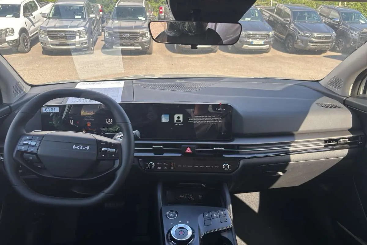 Vue intérieure avant du Kia Sportage gris céramique 2026, avec tableau de bord numérique et écran tactile large.